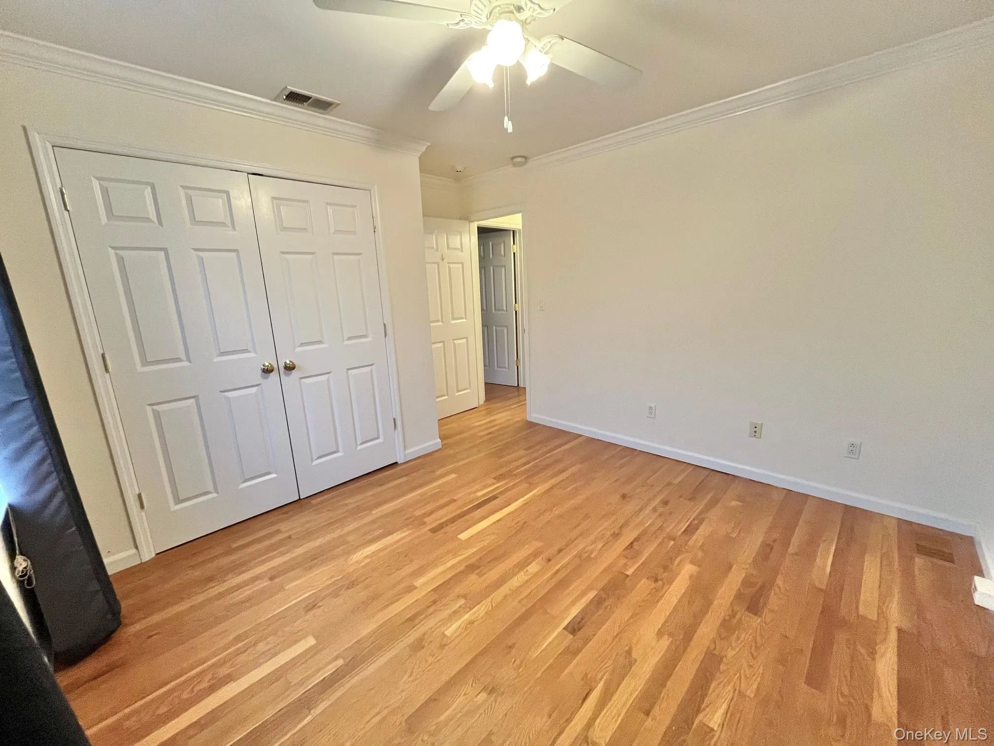 Unfurnished bedroom with ornamental molding, light wood-style floors, ceiling fan, and a closet Unfurnished bedroom with ornamental molding, light wood-style floors, ceiling fan, and a closet