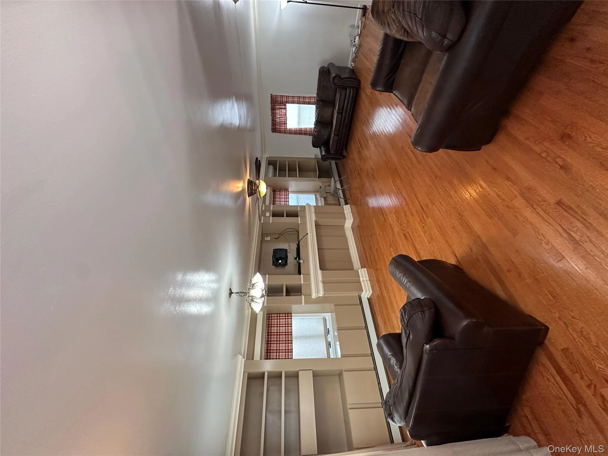Living room featuring light wood-style floors, a chandelier, a baseboard radiator, and a ceiling fan Living room featuring light wood-style floors, a chandelier, a baseboard radiator, and a ceiling fan