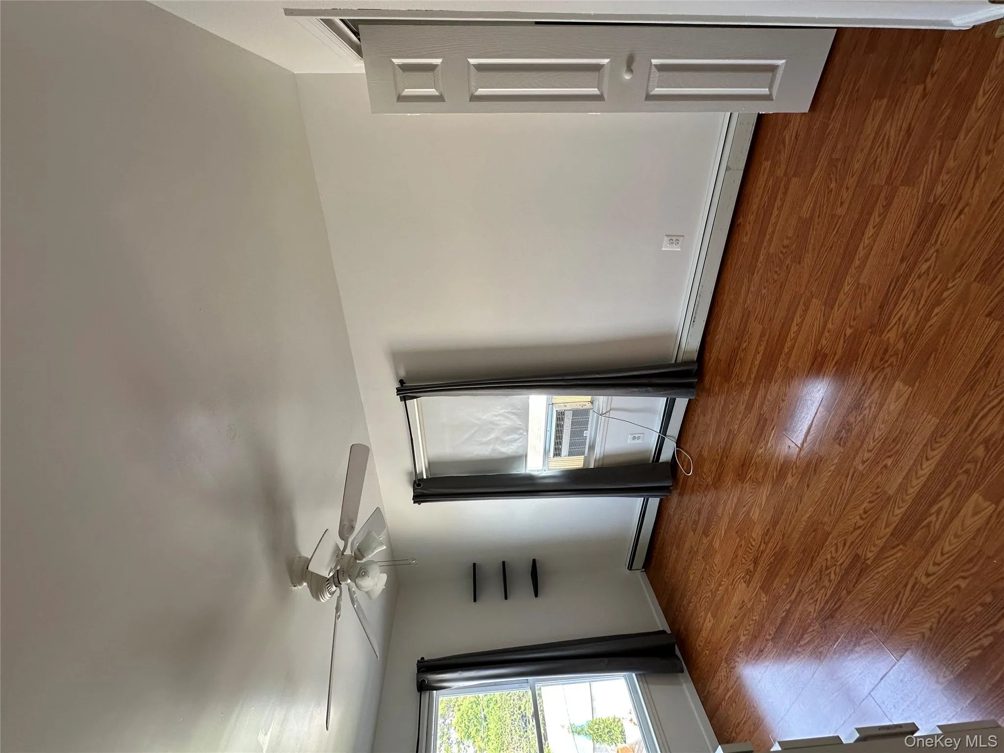 Empty room featuring a baseboard radiator, wood finished floors, ceiling fan, and cooling unit Empty room featuring a baseboard radiator, wood finished floors, ceiling fan, and cooling unit