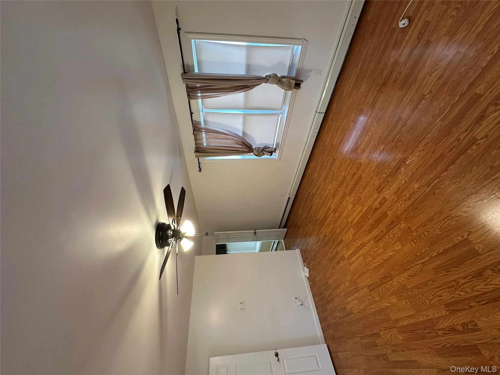 Empty room with wood finished floors, ceiling fan, and a baseboard heating unit Empty room with wood finished floors, ceiling fan, and a baseboard heating unit