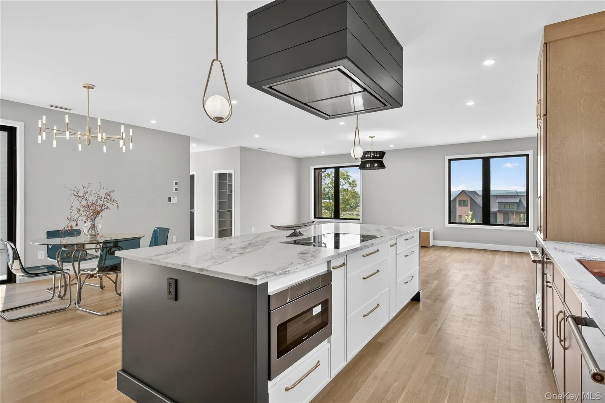 Kitchen with light stone counters, pendant lighting, premium range hood, light wood-style floors, and recessed lighting Kitchen with light stone counters, pendant lighting, premium range hood, light wood-style floors, and recessed lighting