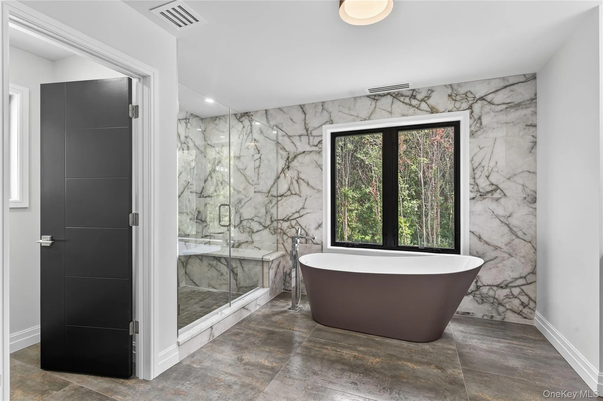 Bathroom with a marble finish shower, a freestanding tub, and recessed lighting Bathroom with a marble finish shower, a freestanding tub, and recessed lighting