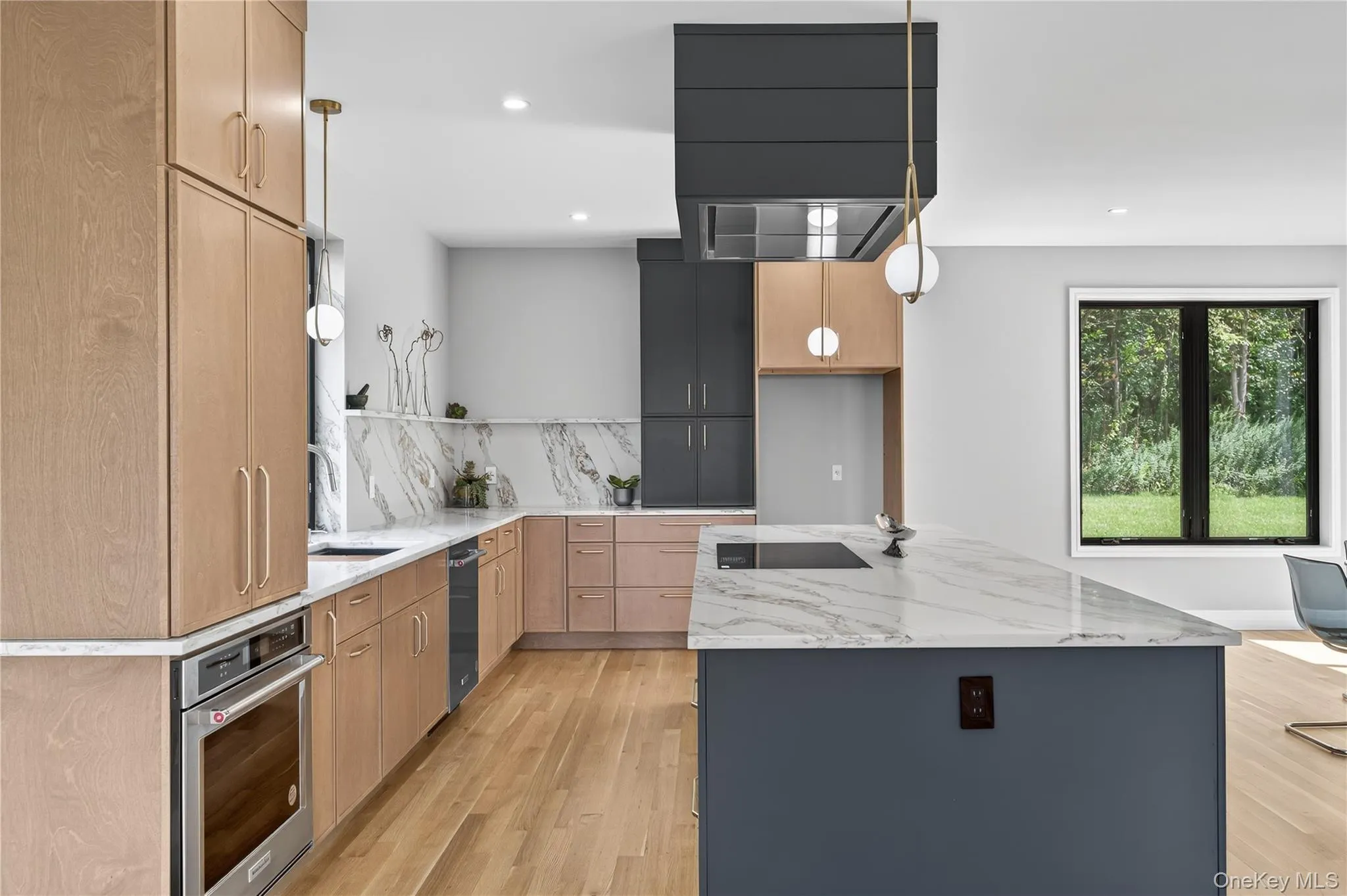 Kitchen featuring light stone countertops, hanging light fixtures, light wood-style flooring, a kitchen island, and oven Kitchen featuring light stone countertops, hanging light fixtures, light wood-style flooring, a kitchen island, and oven