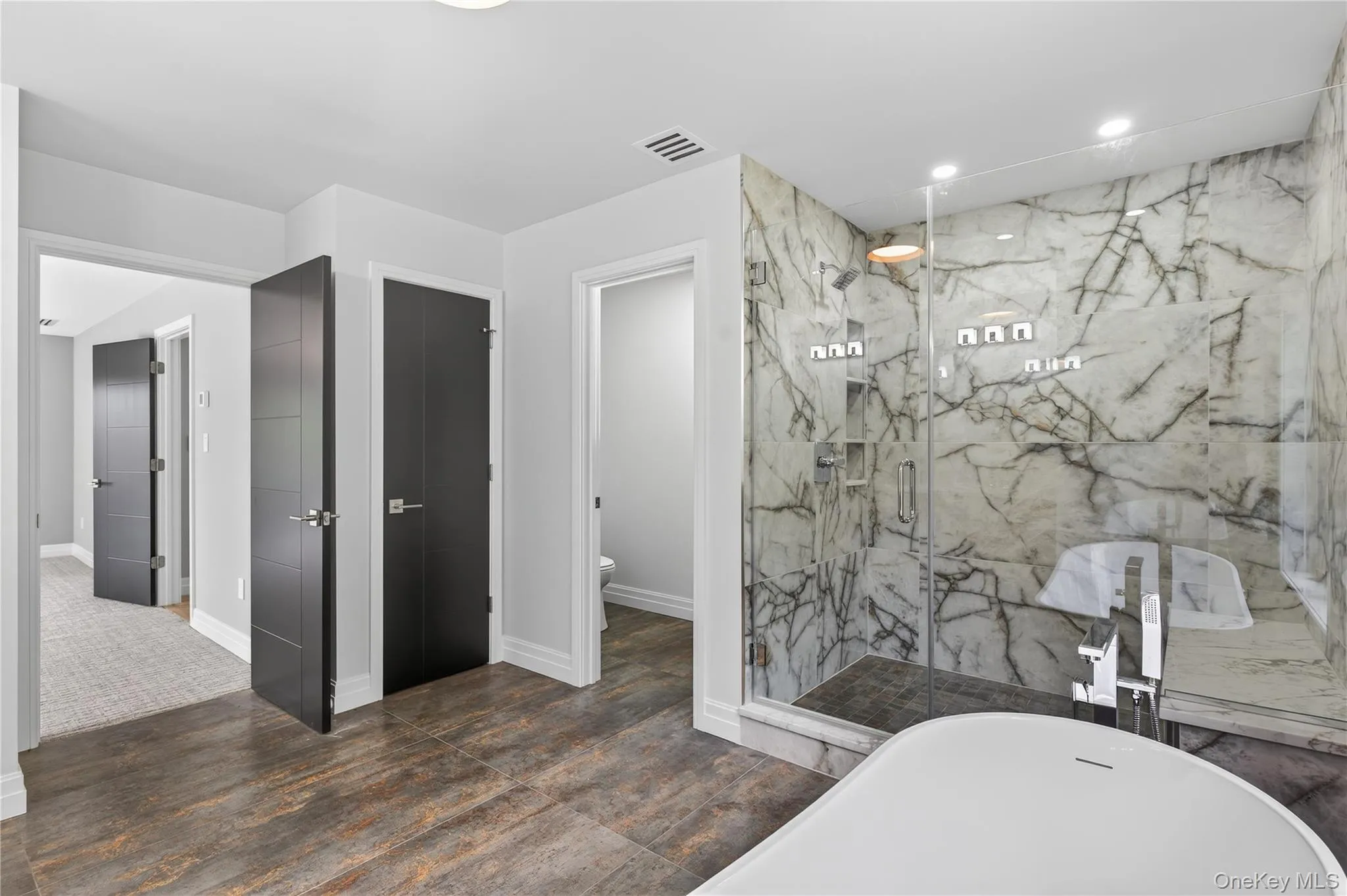 Bathroom featuring a freestanding bath, a marble finish shower, recessed lighting, and dark wood-style flooring Bathroom featuring a freestanding bath, a marble finish shower, recessed lighting, and dark wood-style flooring
