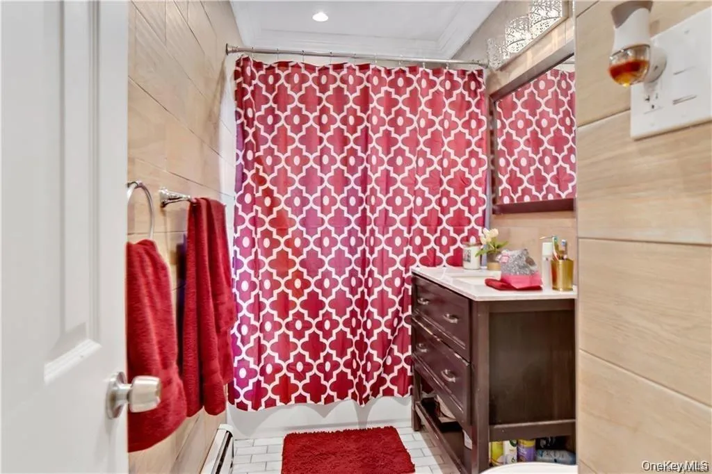 Bathroom featuring baseboard heating, vanity, and crown molding Bathroom featuring baseboard heating, vanity, and crown molding