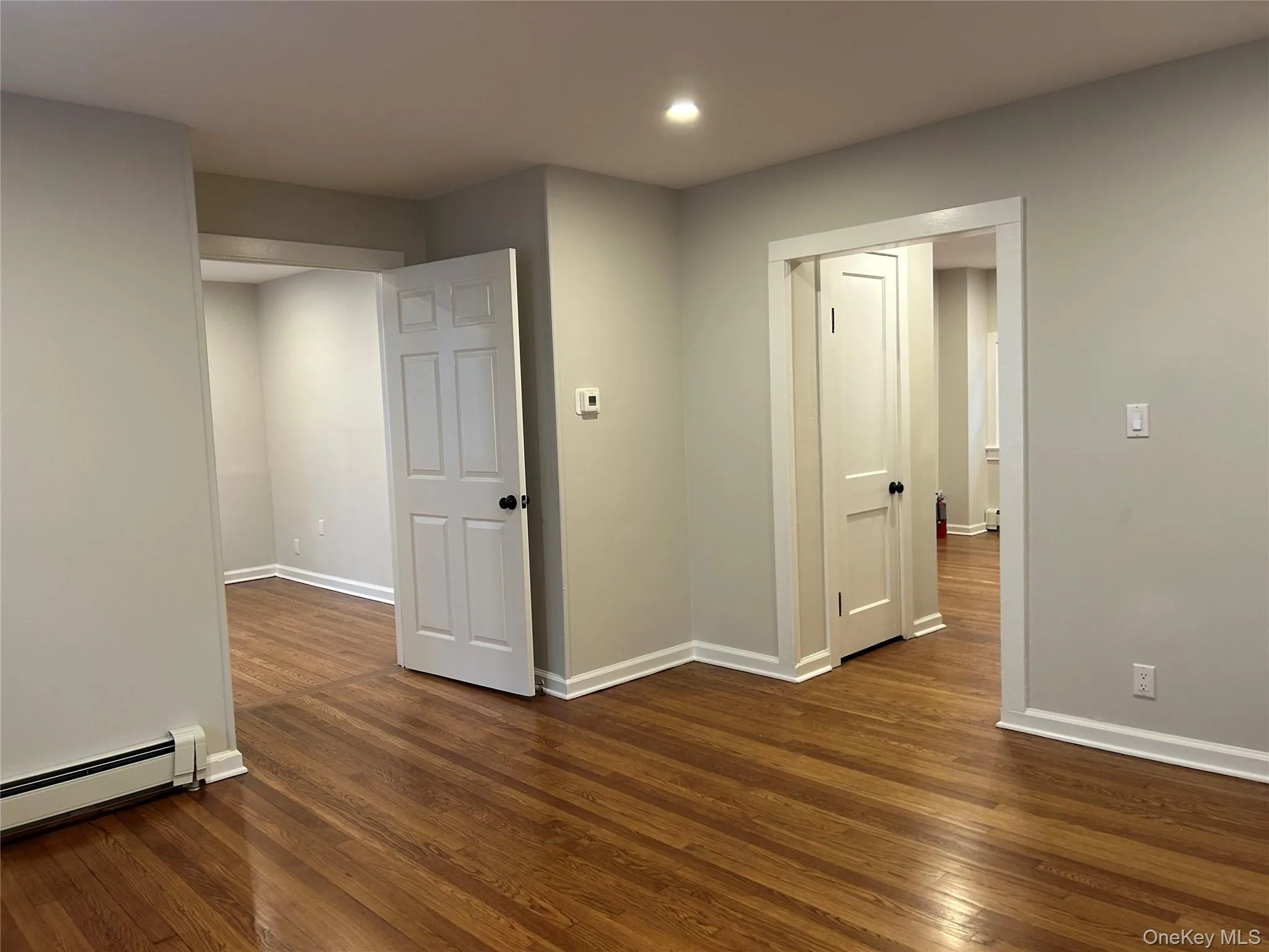 Living room with dark wood-style flooring, a baseboard radiator, and recessed lighting Living room with dark wood-style flooring, a baseboard radiator, and recessed lighting