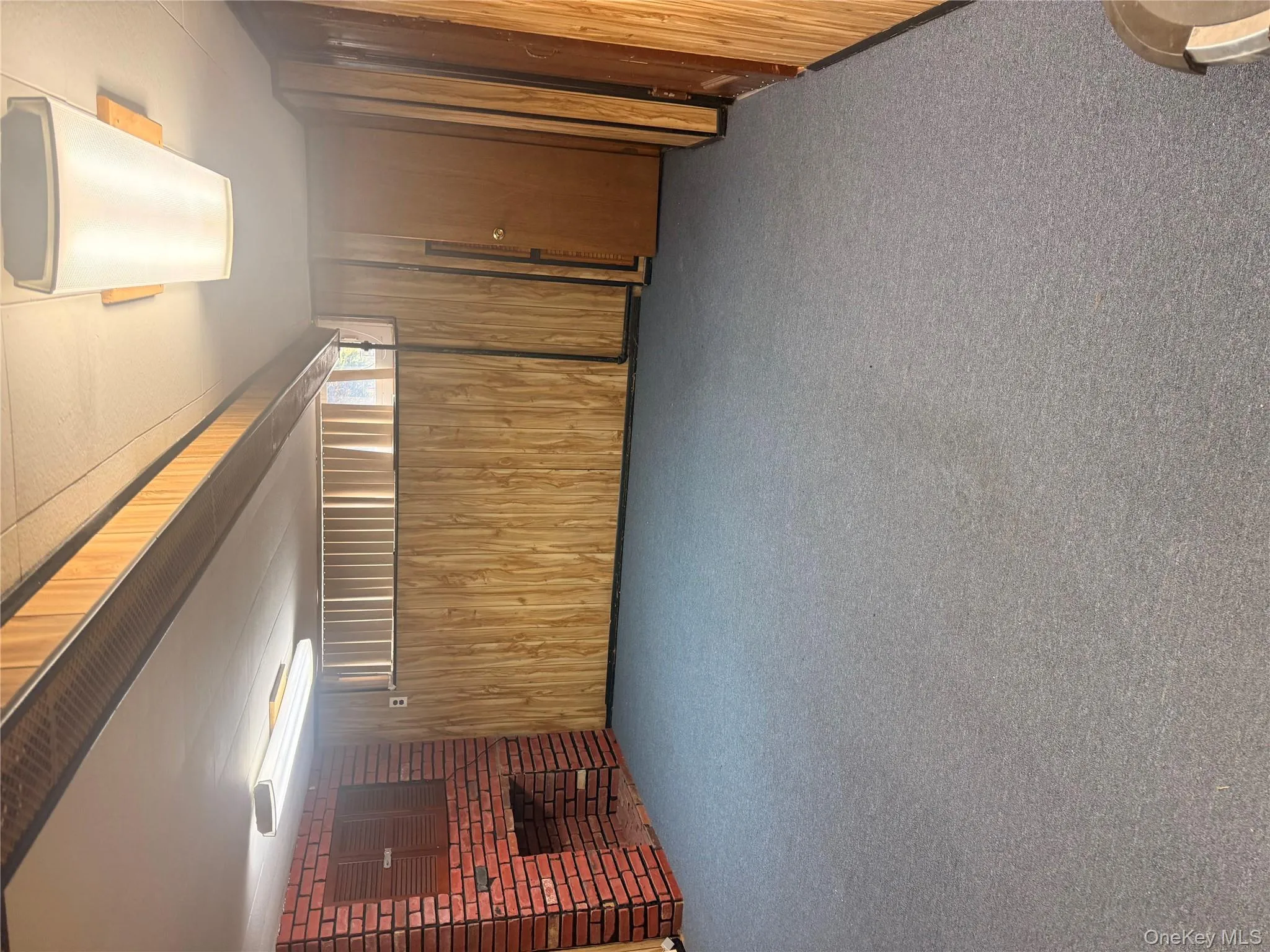 Below grade area featuring a brick fireplace, wooden walls, and carpet Below grade area featuring a brick fireplace, wooden walls, and carpet