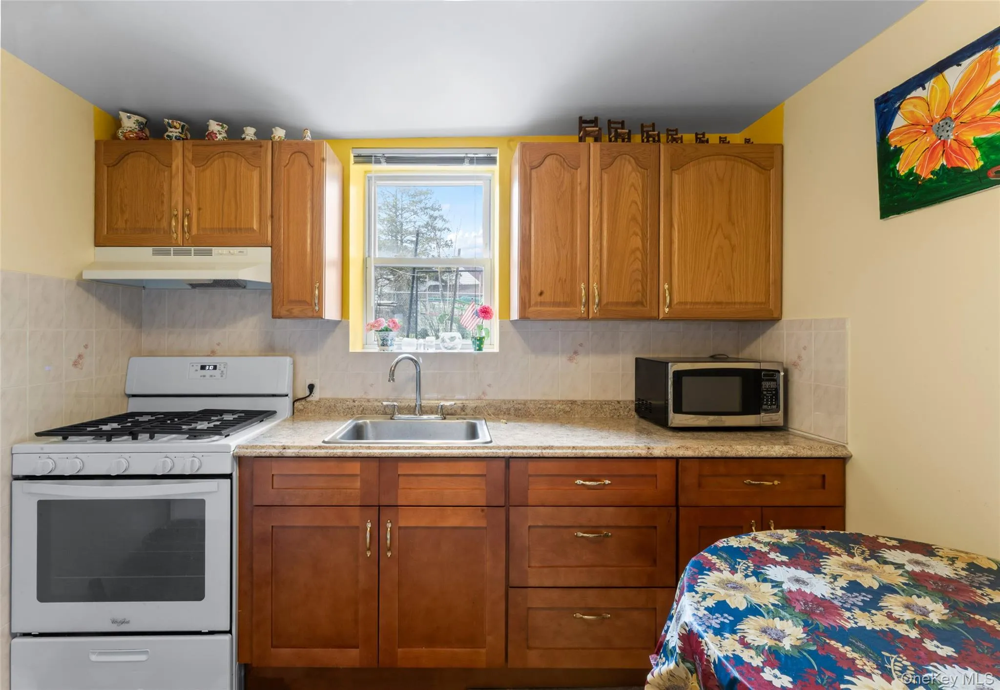 Kitchen with white gas range oven, wood finish cabinets, stainless steel microwave, and tasteful backsplash Kitchen with white gas range oven, wood finish cabinets, stainless steel microwave, and tasteful backsplash