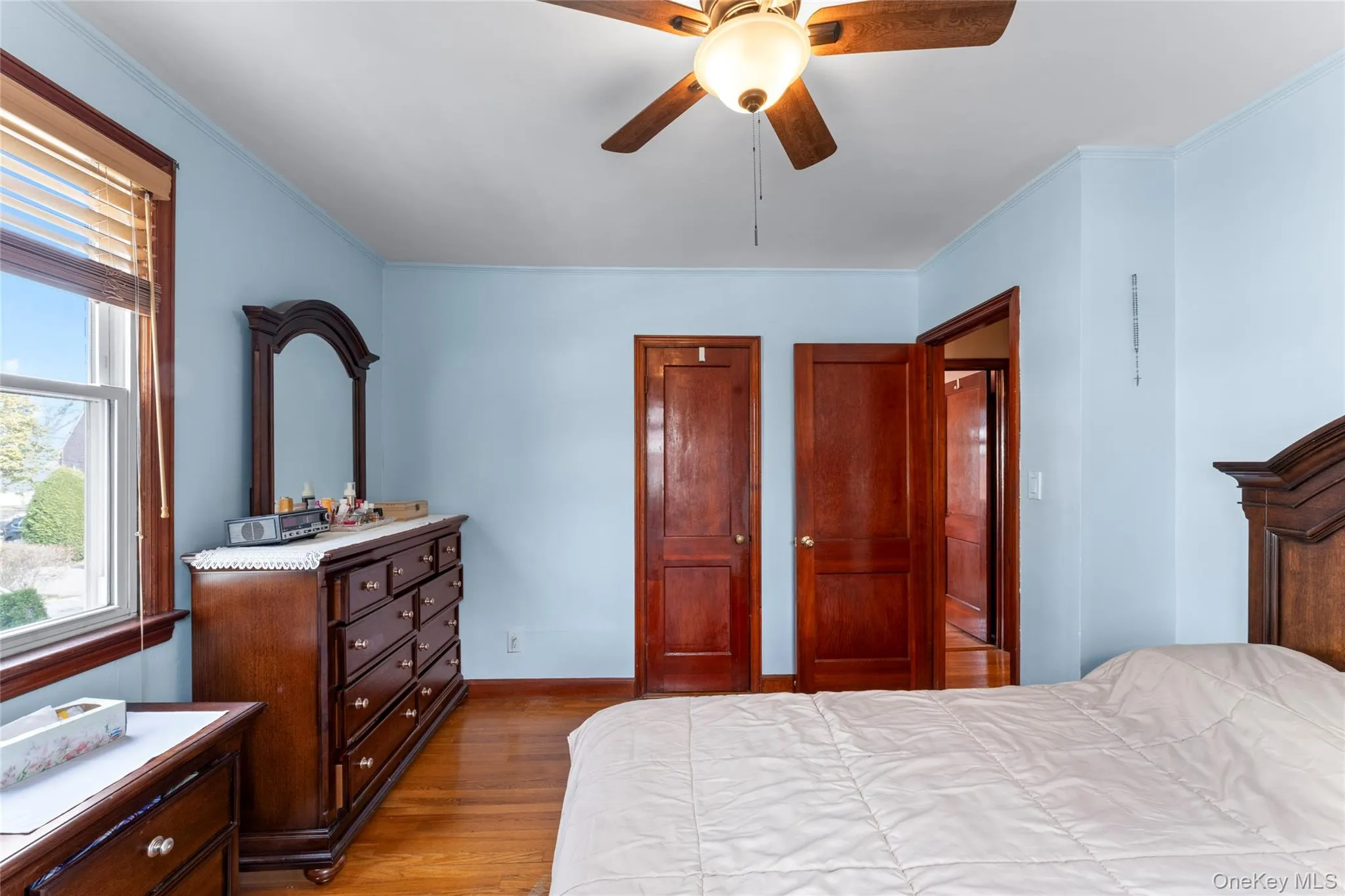 Bedroom featuring a closet, light wood finished floors, ceiling fan, and ornamental molding Bedroom featuring a closet, light wood finished floors, ceiling fan, and ornamental molding