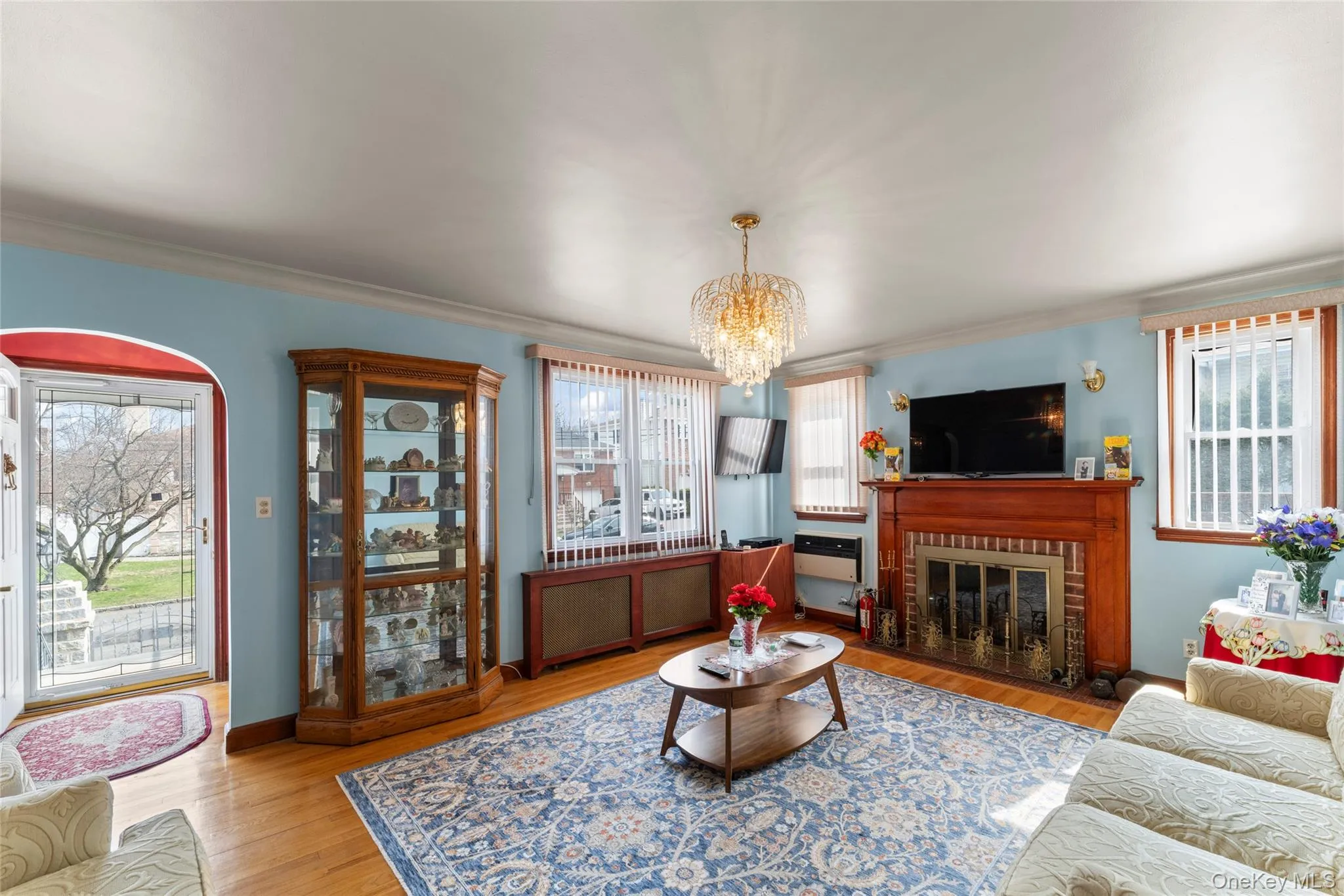 Living room with light wood-style floors, a chandelier, a brick fireplace, and crown molding~All new Windows Living room with light wood-style floors, a chandelier, a brick fireplace, and crown molding~All new Windows