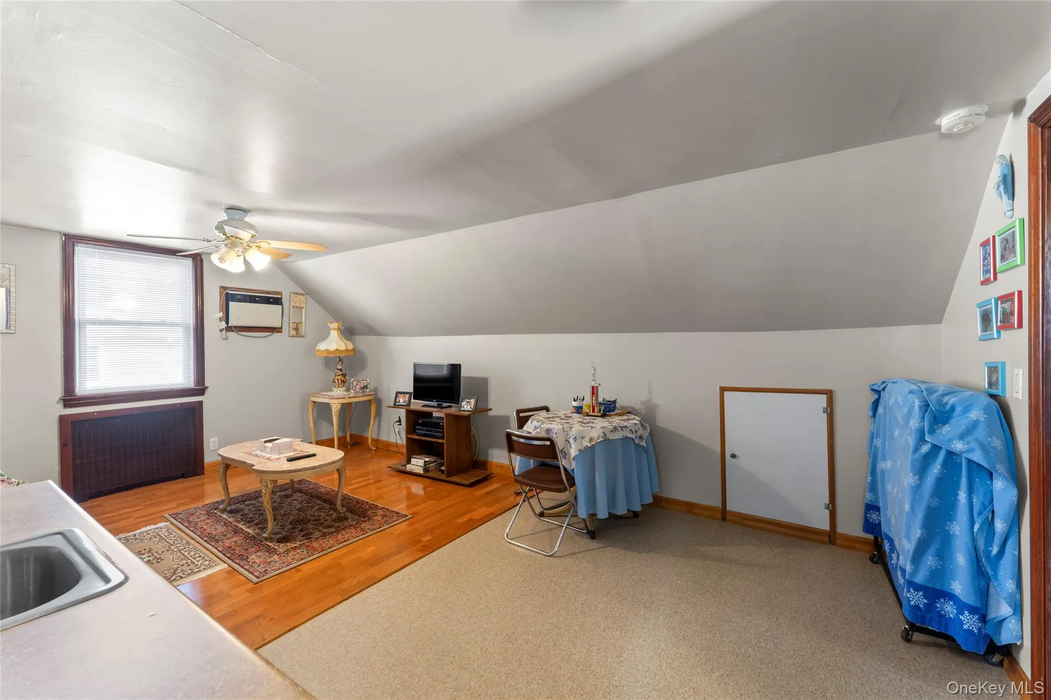 Home office featuring radiator, ceiling fan, vaulted ceiling, and light wood-style floors Home office featuring radiator, ceiling fan, vaulted ceiling, and light wood-style floors
