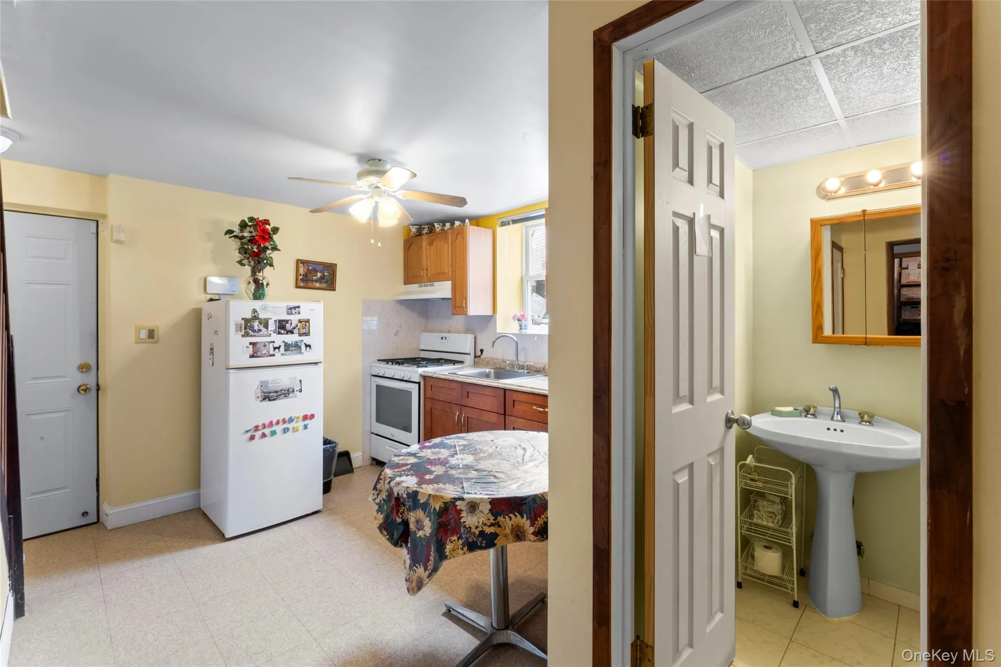 Kitchen featuring white appliances, light countertops, ceiling fan, wood finish cabinetry, and light flooring Kitchen featuring white appliances, light countertops, ceiling fan, wood finish cabinetry, and light flooring