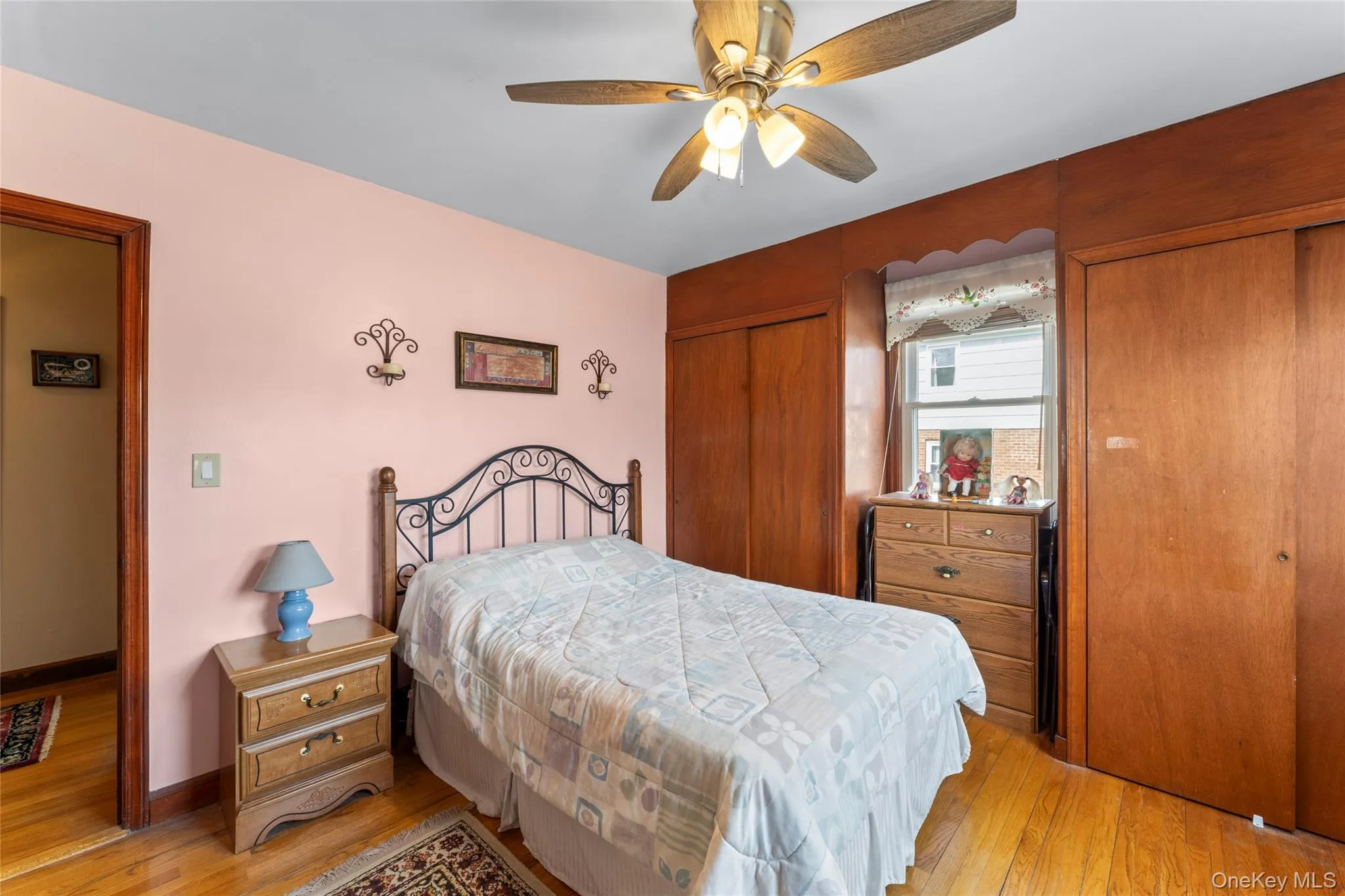 Bedroom featuring two closets, light wood-style floors, and a ceiling fan Bedroom featuring two closets, light wood-style floors, and a ceiling fan