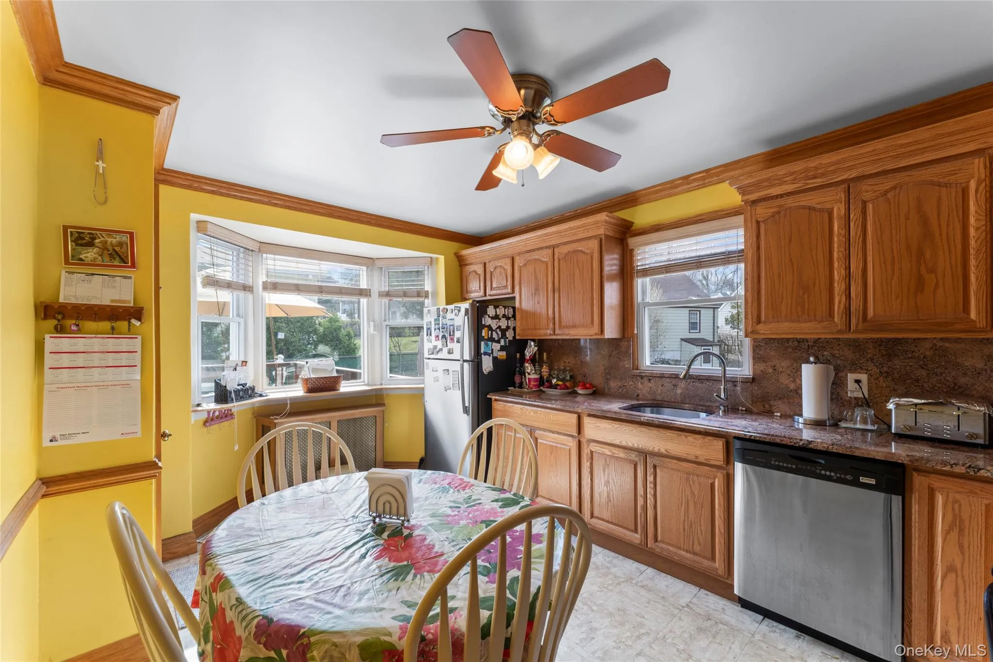 Kitchen featuring dishwasher, freestanding refrigerator, crown molding, plenty of natural light, and wood finish cabinetry~ Kitchen featuring dishwasher, freestanding refrigerator, crown molding, plenty of natural light, and wood finish cabinetry~