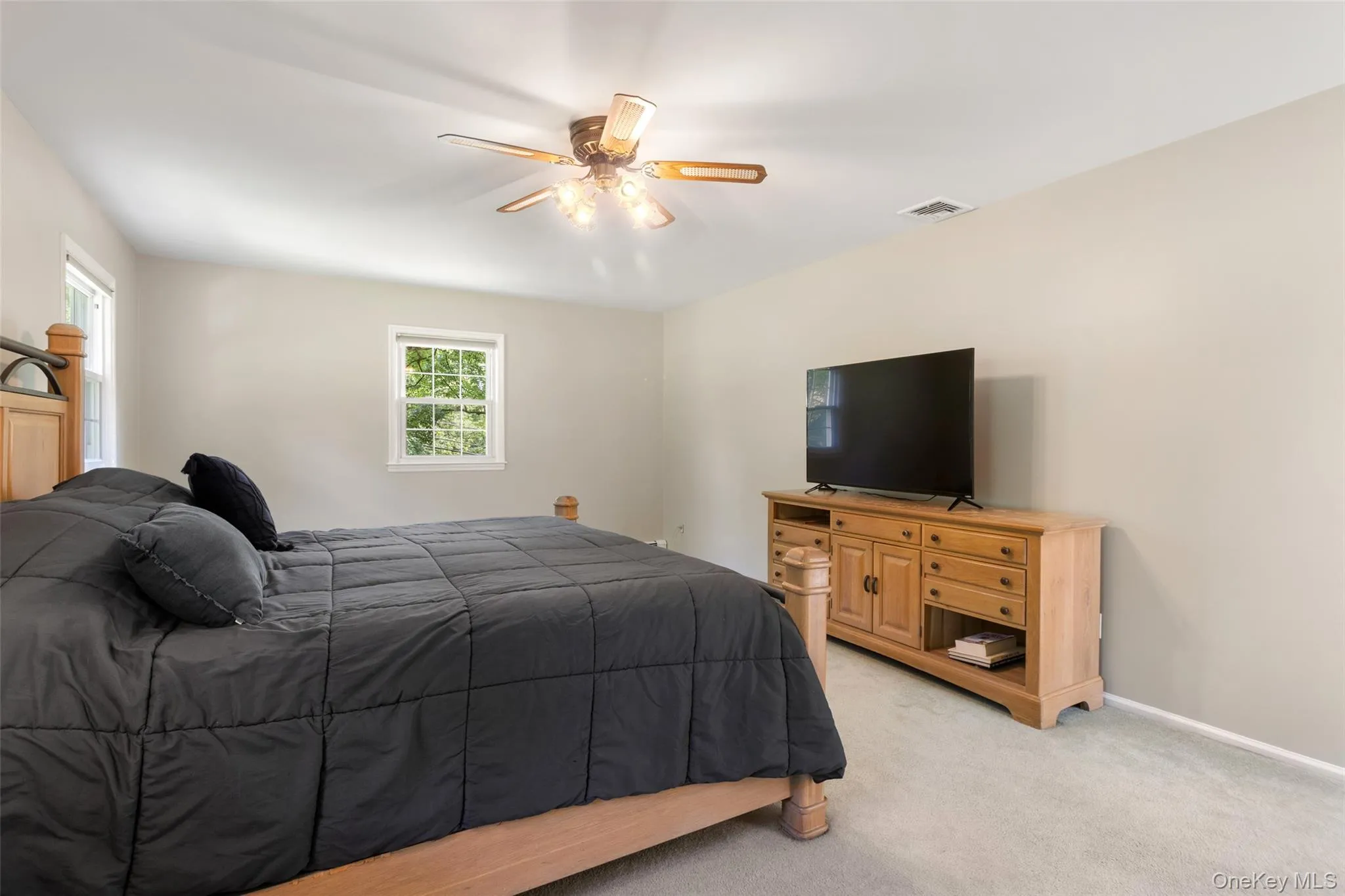 Another view of primary bedroom showing windows, ceiling fan Another view of primary bedroom showing windows, ceiling fan
