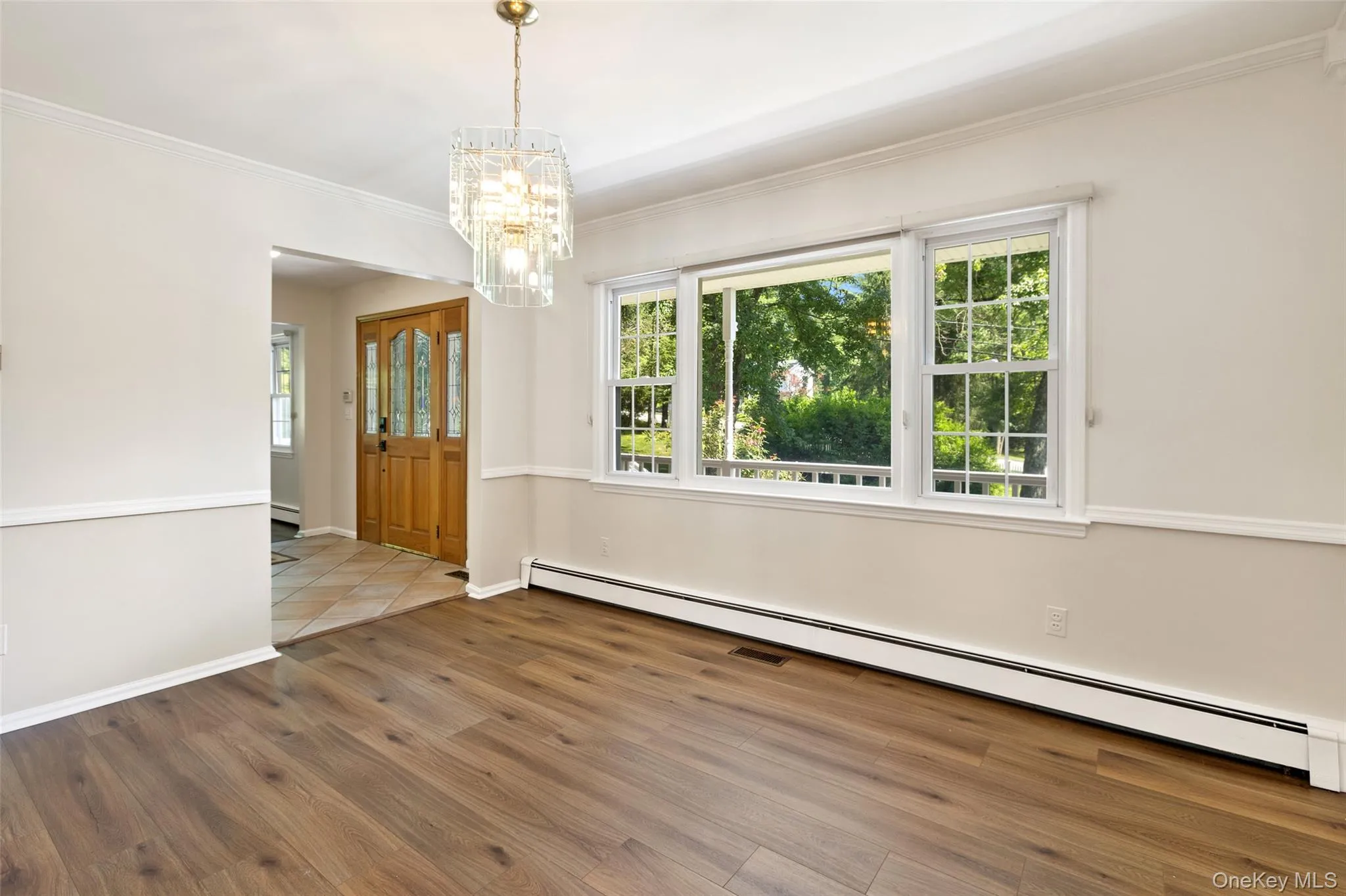 Formal dining room with large window and chandelier flowing into large foyer Formal dining room with large window and chandelier flowing into large foyer