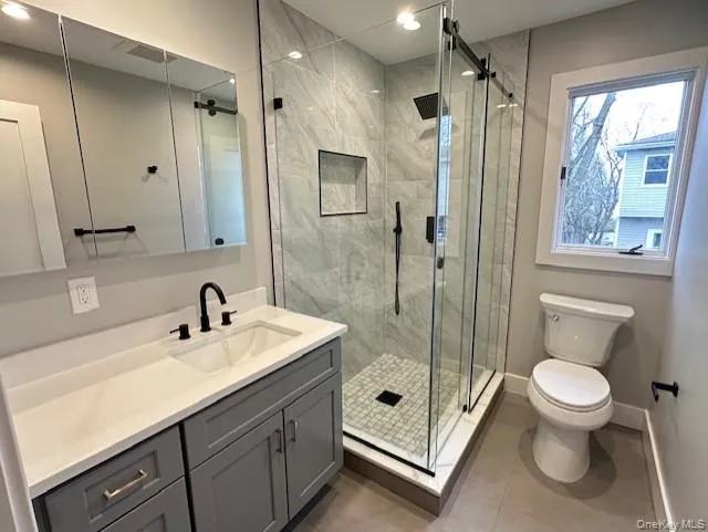 Bathroom with vanity, a marble finish shower, and light tile patterned floors Bathroom with vanity, a marble finish shower, and light tile patterned floors