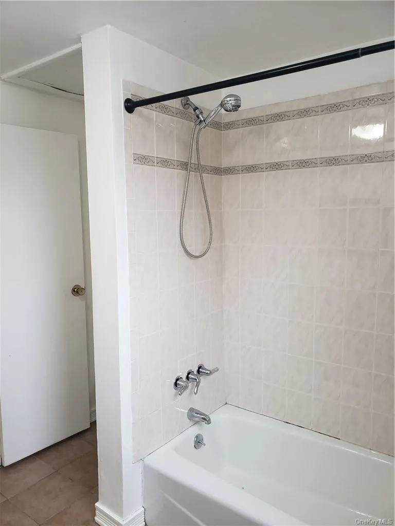 Full bathroom featuring shower / bath combination and tile patterned flooring Full bathroom featuring shower / bath combination and tile patterned flooring