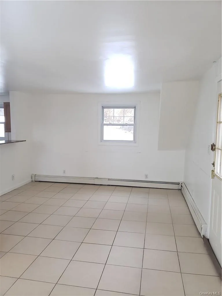 Unfurnished room featuring a baseboard radiator and light tile patterned floors Unfurnished room featuring a baseboard radiator and light tile patterned floors