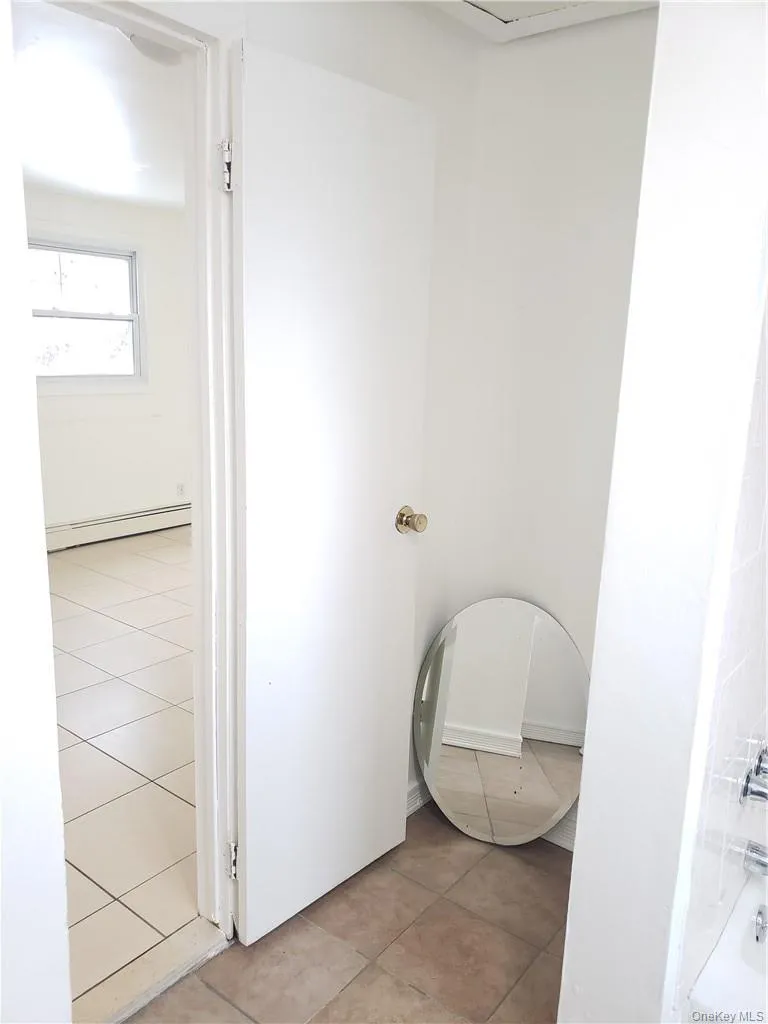 Bathroom with light tile patterned floors, a baseboard heating unit, and a tub Bathroom with light tile patterned floors, a baseboard heating unit, and a tub