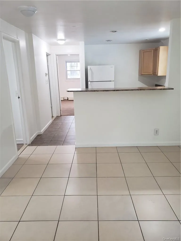 Kitchen with light tile patterned flooring, freestanding refrigerator, and a peninsula Kitchen with light tile patterned flooring, freestanding refrigerator, and a peninsula
