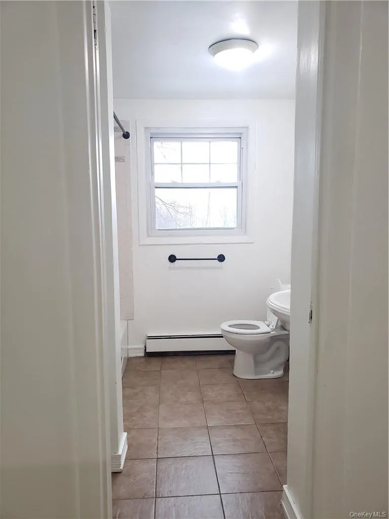 Full bathroom with a baseboard radiator and light tile patterned floors Full bathroom with a baseboard radiator and light tile patterned floors