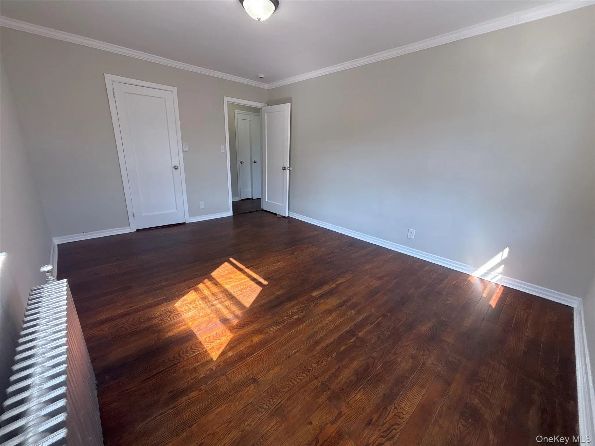 Unfurnished room with ornamental molding and dark wood-type flooring Unfurnished room with ornamental molding and dark wood-type flooring