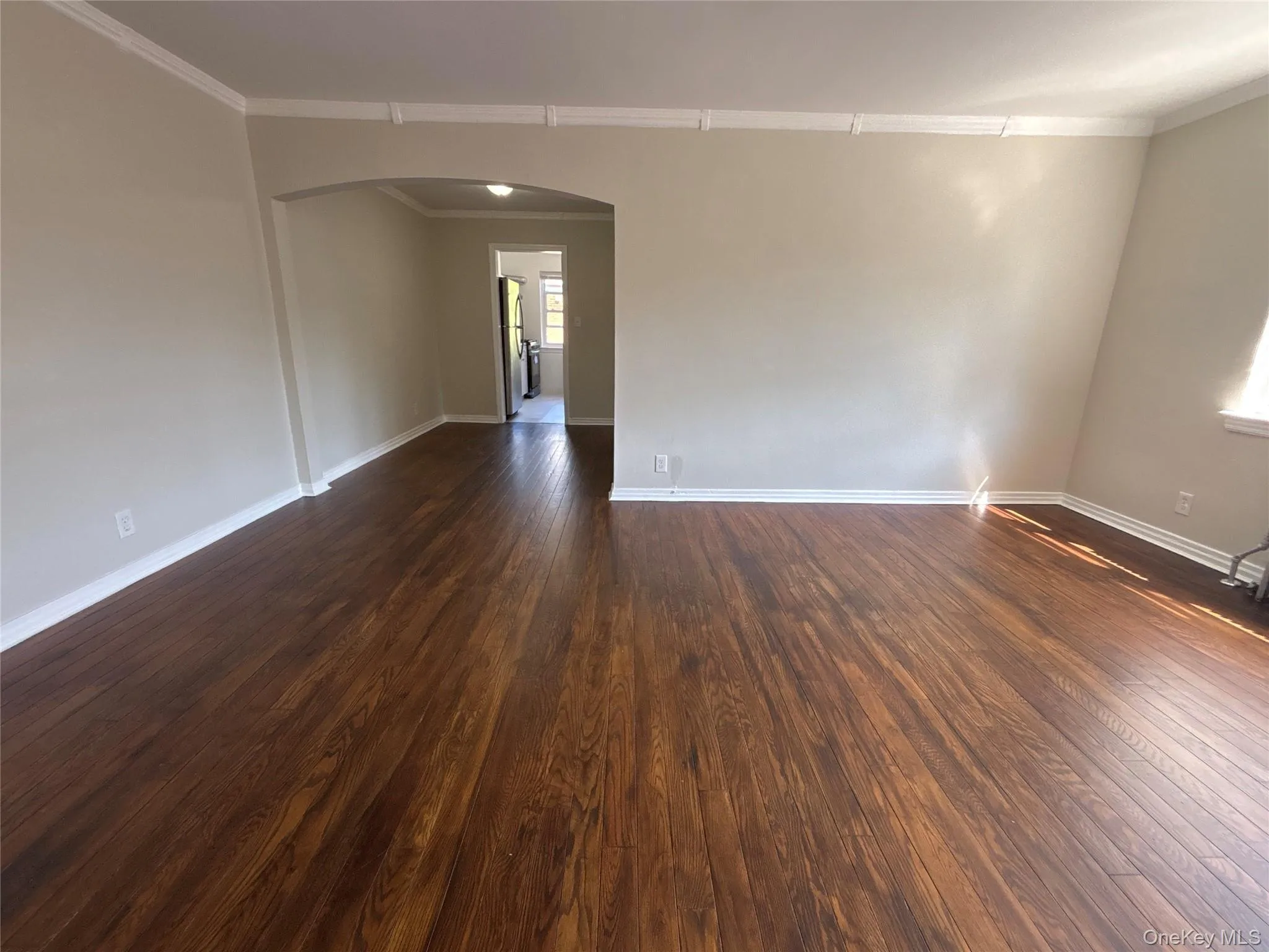 Spare room with arched walkways, ornamental molding, and dark wood-type flooring Spare room with arched walkways, ornamental molding, and dark wood-type flooring
