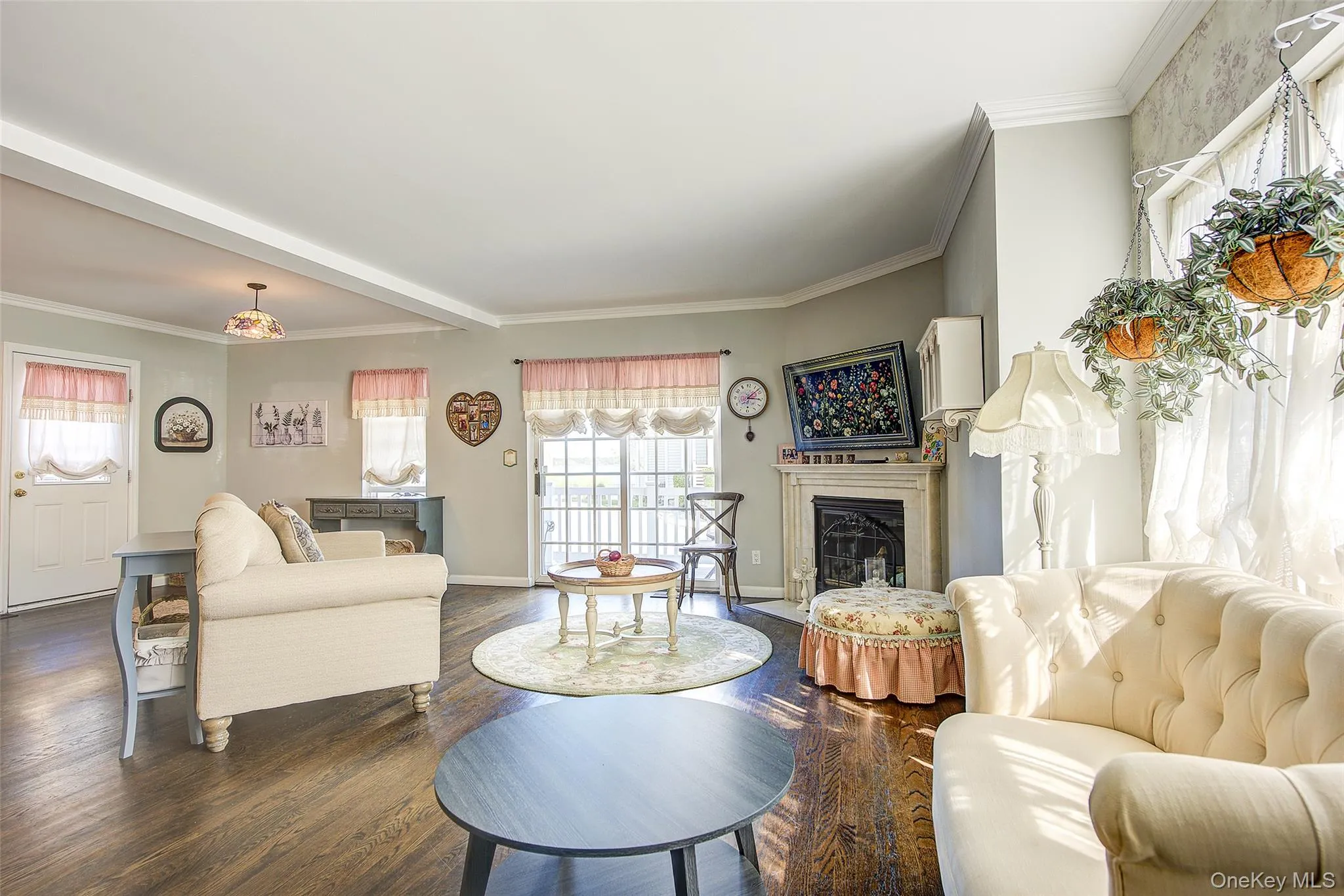 Living area with a fireplace with flush hearth, ornamental molding, plenty of natural light, and wood finished floors Living area with a fireplace with flush hearth, ornamental molding, plenty of natural light, and wood finished floors