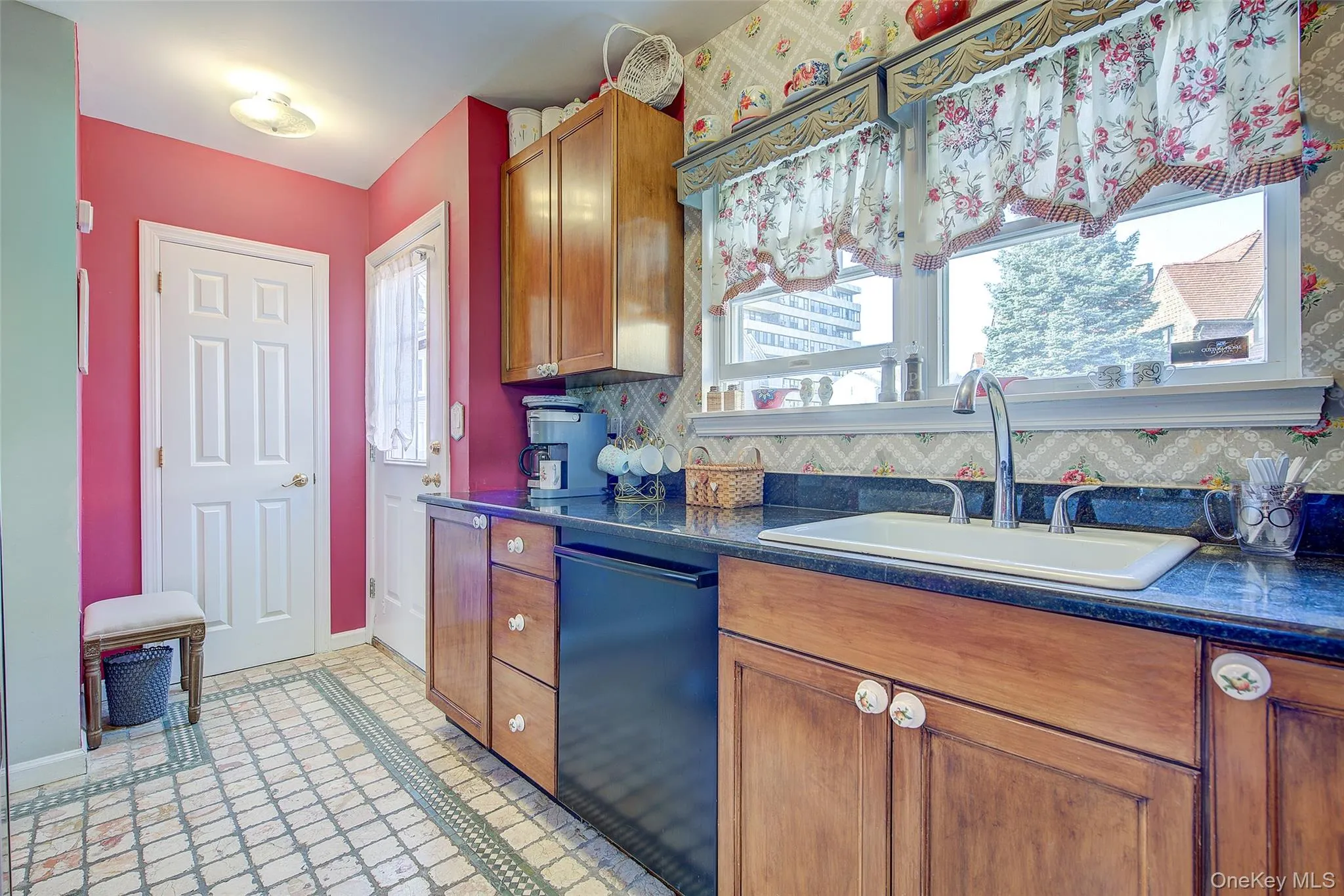 Kitchen with brown cabinetry, decorative backsplash, dishwasher, and light tile patterned flooring Kitchen with brown cabinetry, decorative backsplash, dishwasher, and light tile patterned flooring