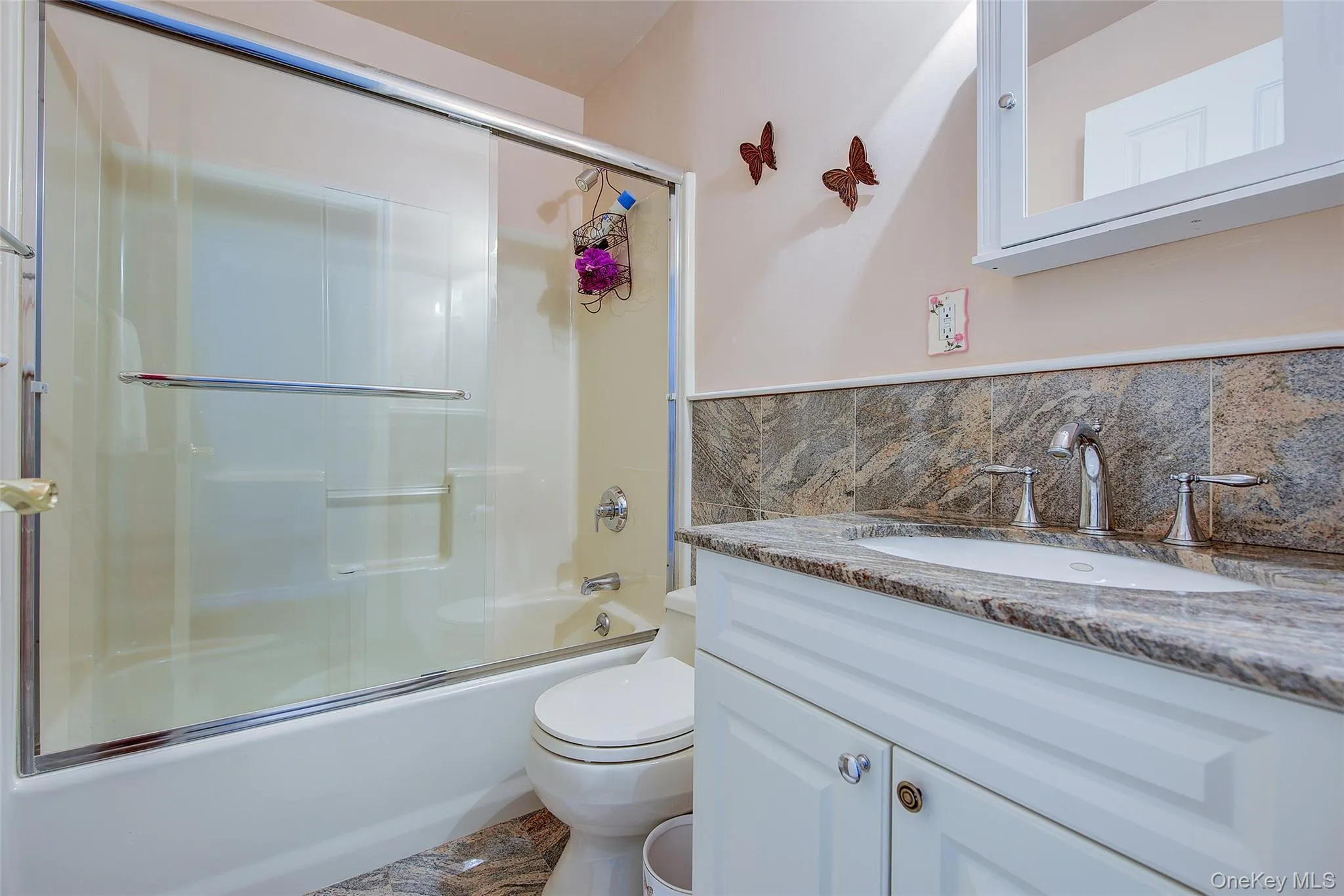 Bathroom with combined bath / shower with glass door, vanity, and tile walls Bathroom with combined bath / shower with glass door, vanity, and tile walls