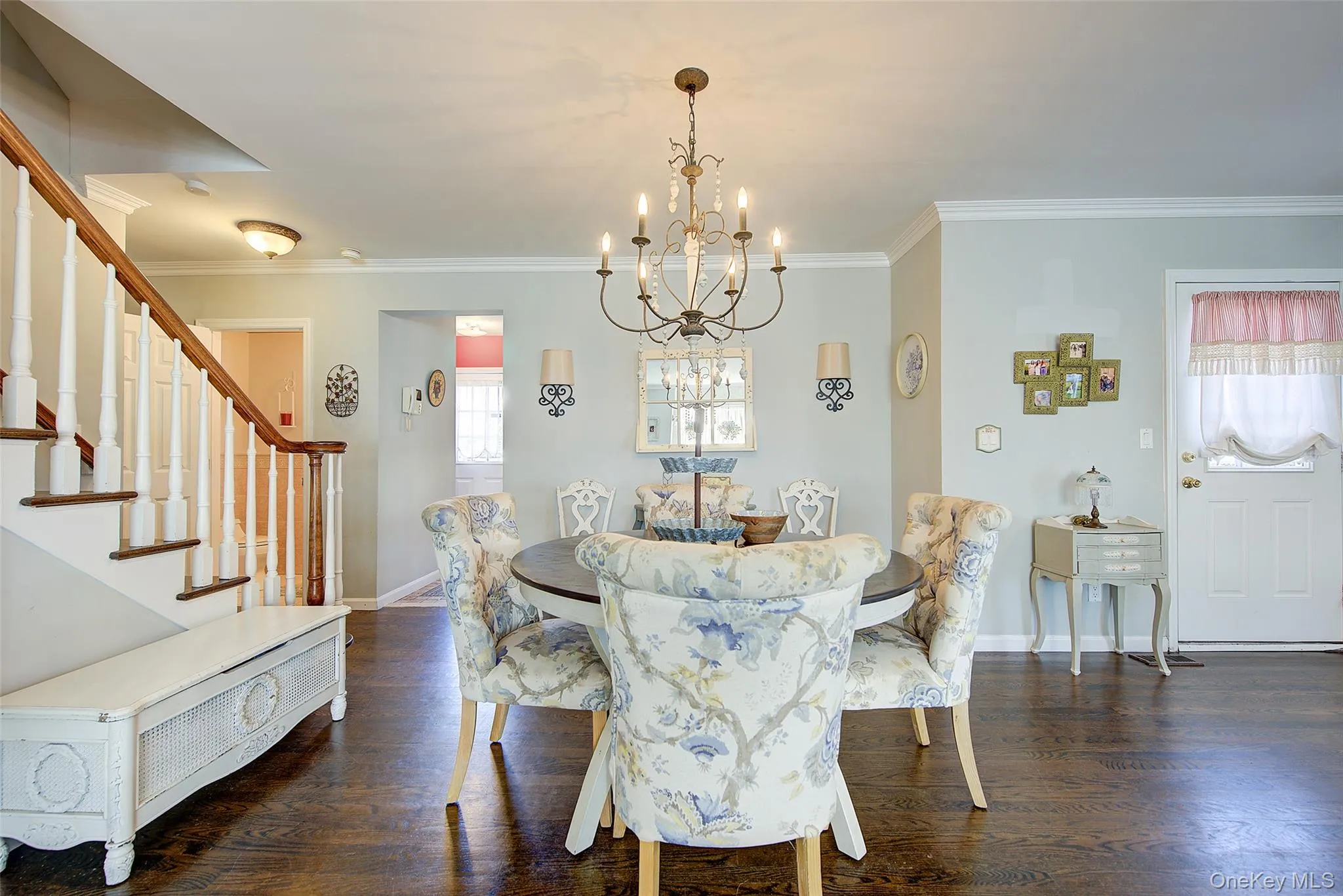 Dining room with dark wood-style floors, ornamental molding, a chandelier, and stairs Dining room with dark wood-style floors, ornamental molding, a chandelier, and stairs