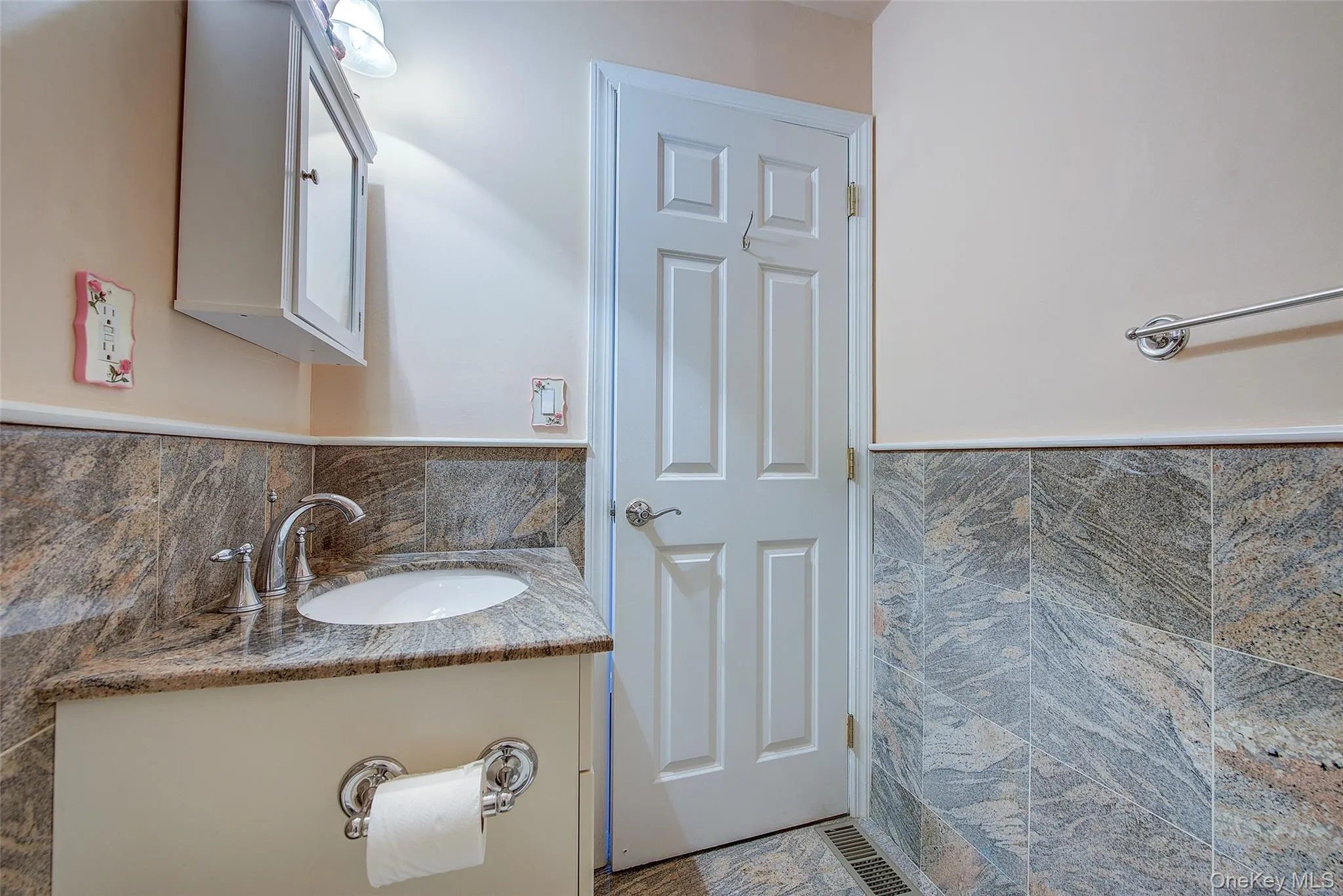 Bathroom featuring tile walls, vanity, and wainscoting Bathroom featuring tile walls, vanity, and wainscoting