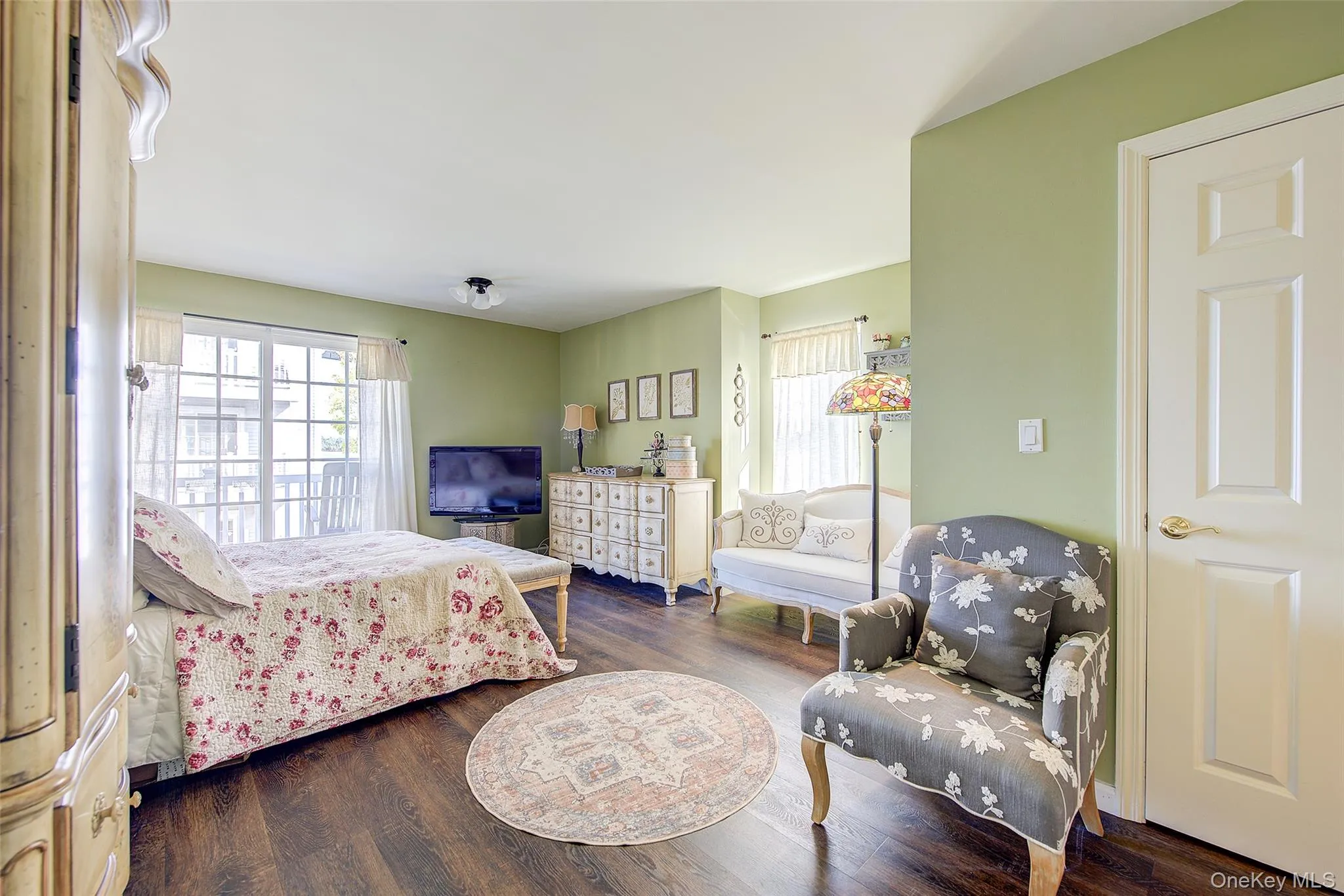 Bedroom with multiple windows and dark wood-style floors Bedroom with multiple windows and dark wood-style floors