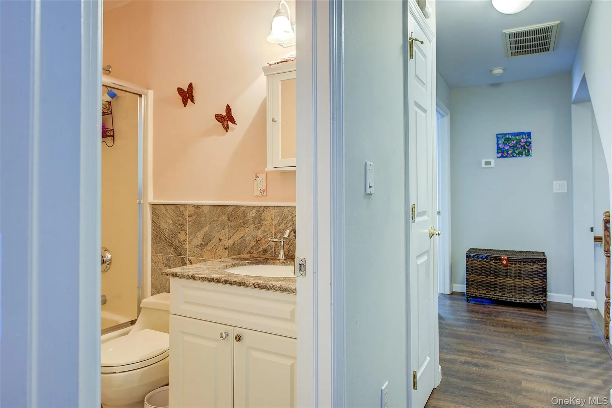 Full bath featuring vanity, combined bath / shower with glass door, dark wood-style floors, and tile walls Full bath featuring vanity, combined bath / shower with glass door, dark wood-style floors, and tile walls