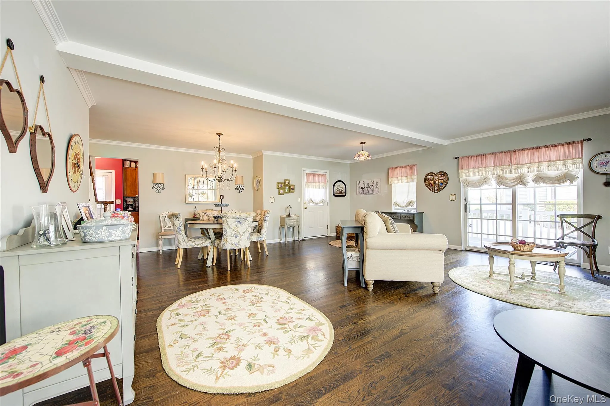 Living area with crown molding, dark wood-style floors, a chandelier, healthy amount of natural light, and beamed ceiling Living area with crown molding, dark wood-style floors, a chandelier, healthy amount of natural light, and beamed ceiling