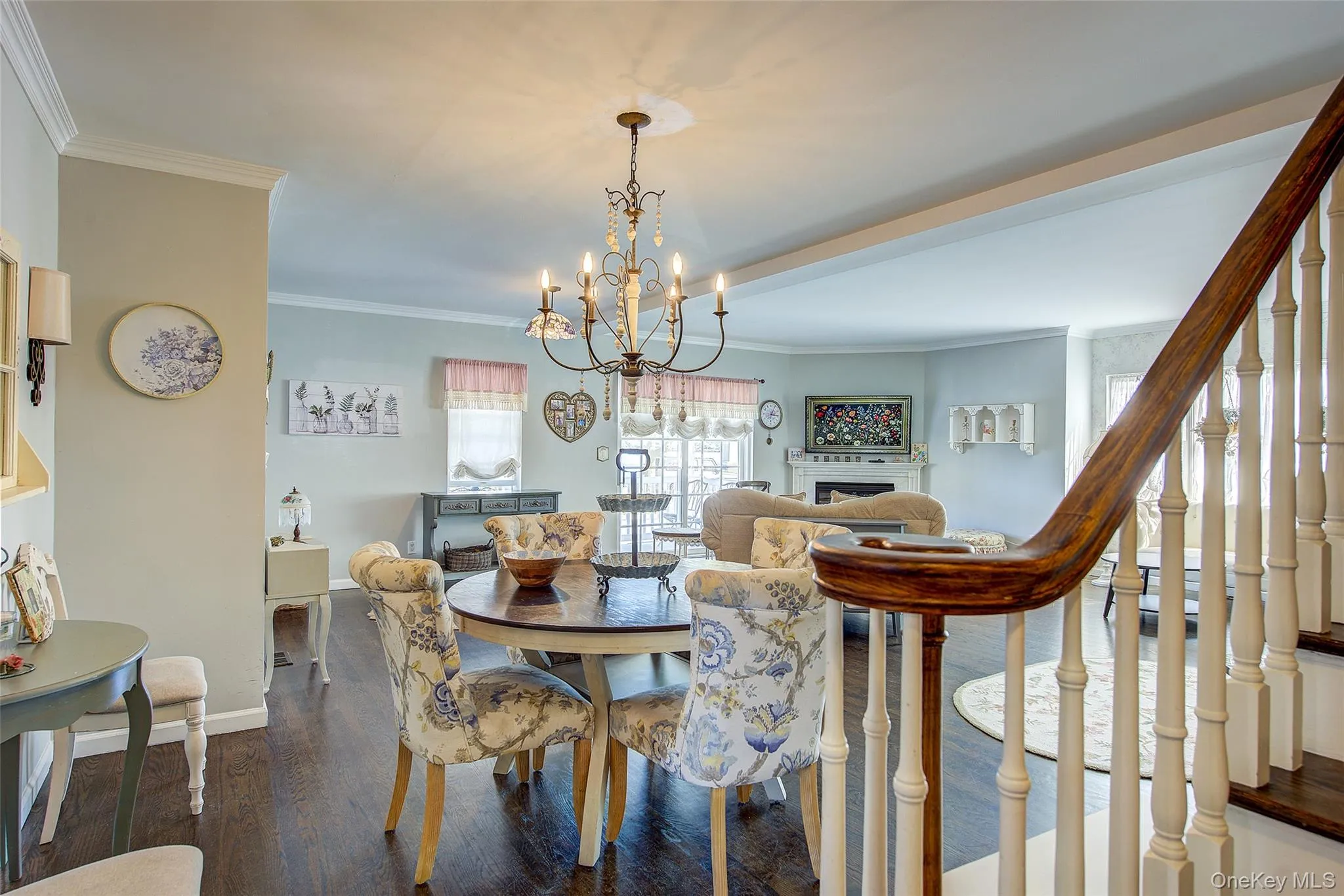 Dining room featuring ornamental molding, dark wood-style flooring, a fireplace, a chandelier, and stairway Dining room featuring ornamental molding, dark wood-style flooring, a fireplace, a chandelier, and stairway