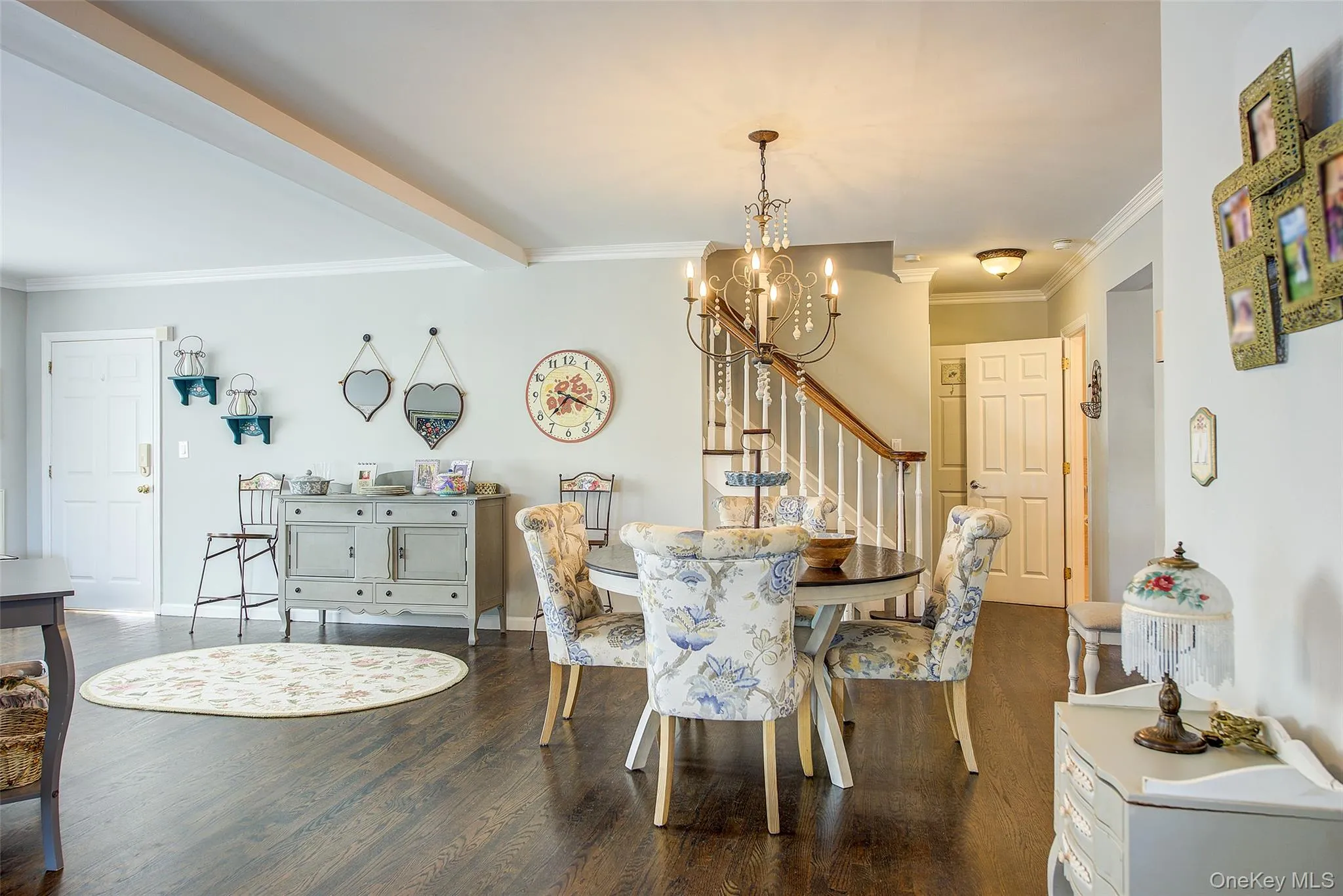 Dining area featuring crown molding, dark wood-style floors, a chandelier, stairway, and beamed ceiling Dining area featuring crown molding, dark wood-style floors, a chandelier, stairway, and beamed ceiling