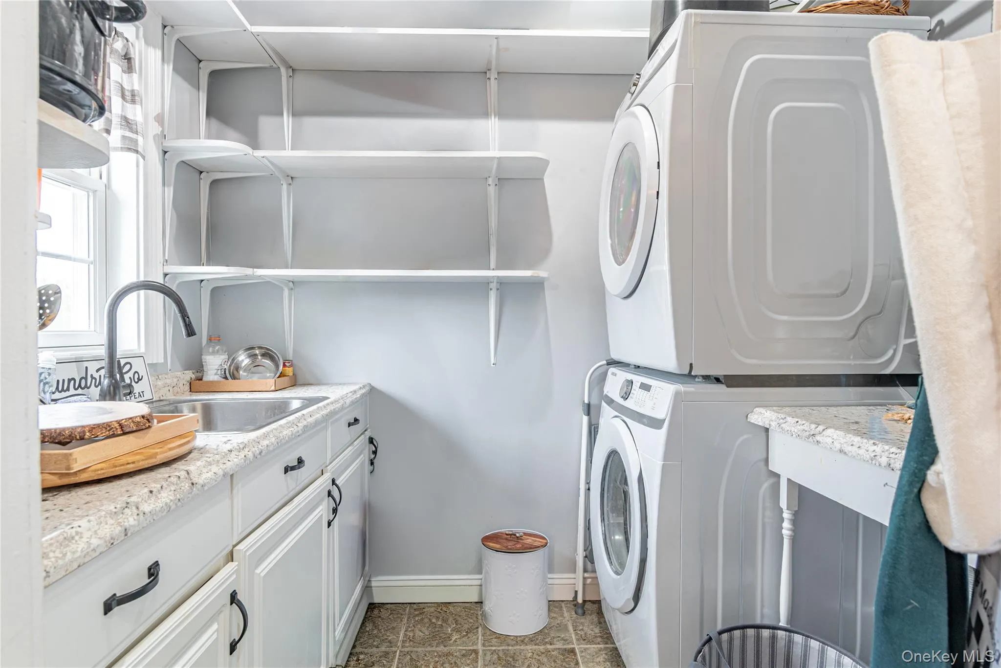 Laundry room featuring stacked washing machine and dryer and a sink Laundry room featuring stacked washing machine and dryer and a sink