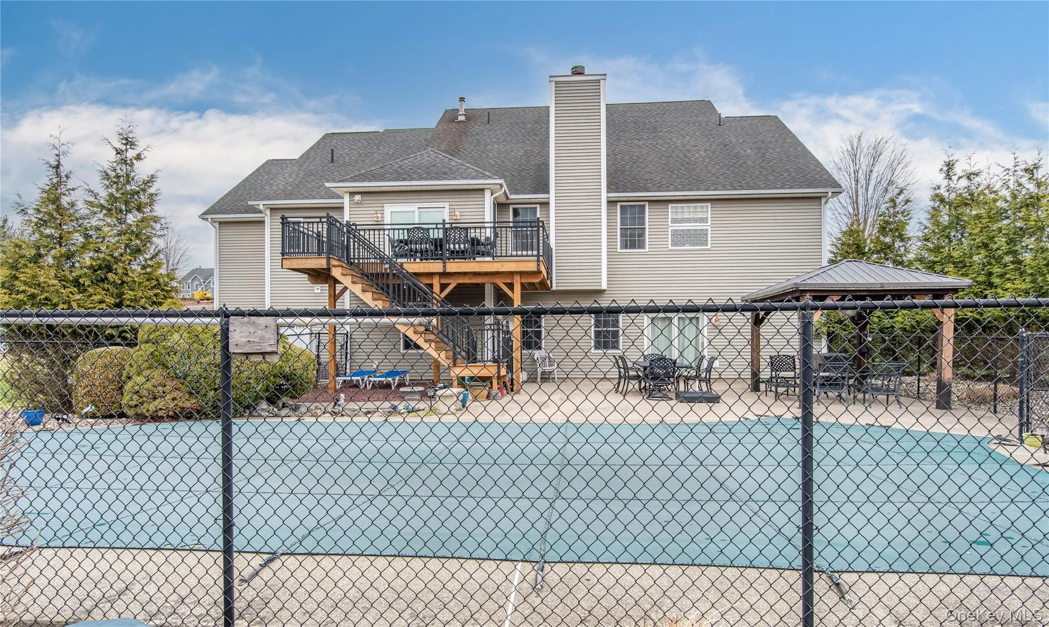 Rear view of property with a patio and in-ground pool, a wooden deck on the second level, a chimney, and a shingled roof Rear view of property with a patio and in-ground pool, a wooden deck on the second level, a chimney, and a shingled roof