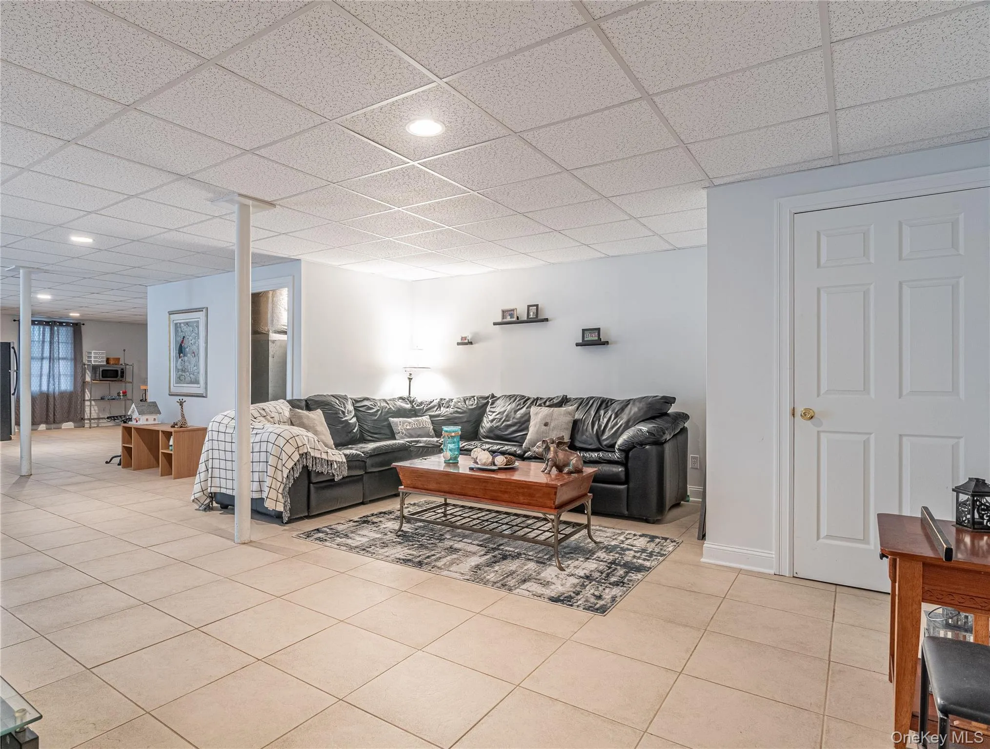 Living area featuring in the finished basement featuring paneled ceiling, light tile patterned flooring, and recessed lighting Living area featuring in the finished basement featuring paneled ceiling, light tile patterned flooring, and recessed lighting