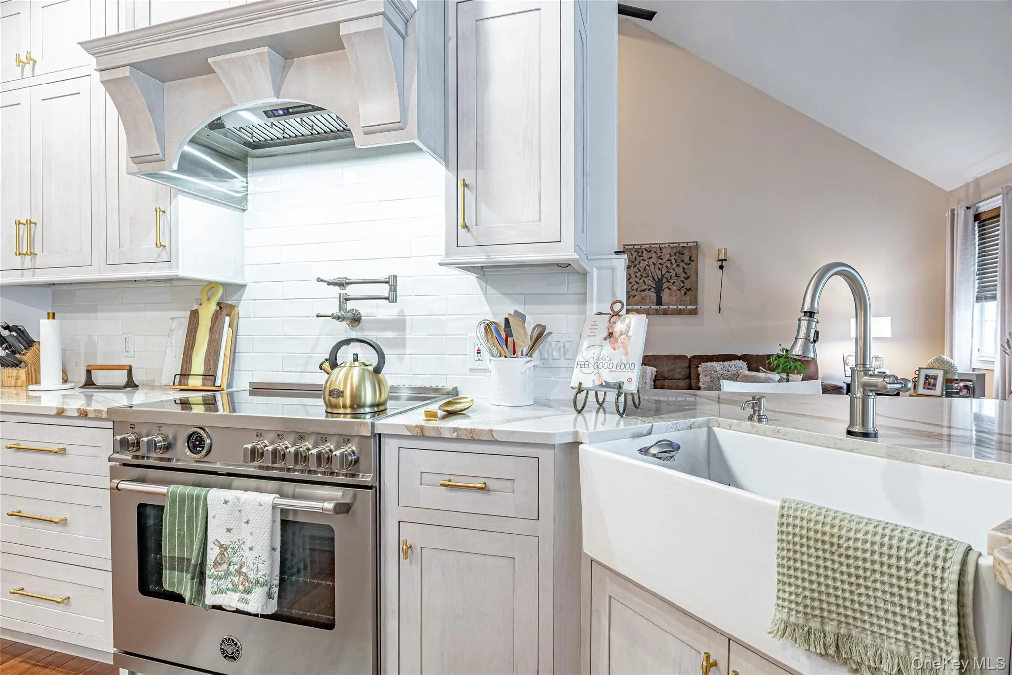 Kitchen with high end stove, light stone countertops, decorative backsplash, lofted ceiling, and white cabinets Kitchen with high end stove, light stone countertops, decorative backsplash, lofted ceiling, and white cabinets