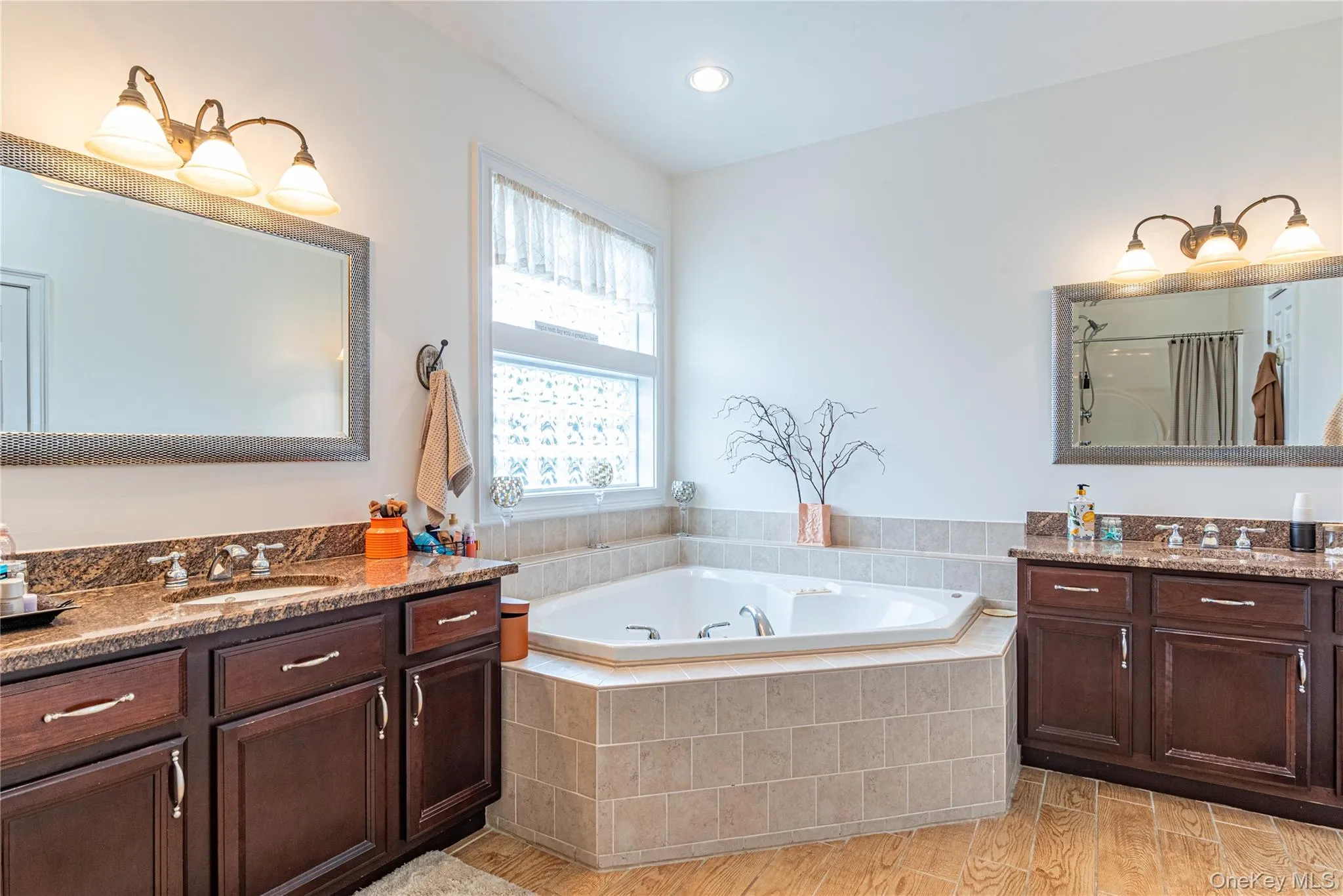 Full bath with light, two vanities, a bath, and curtained shower Full bath with light, two vanities, a bath, and curtained shower