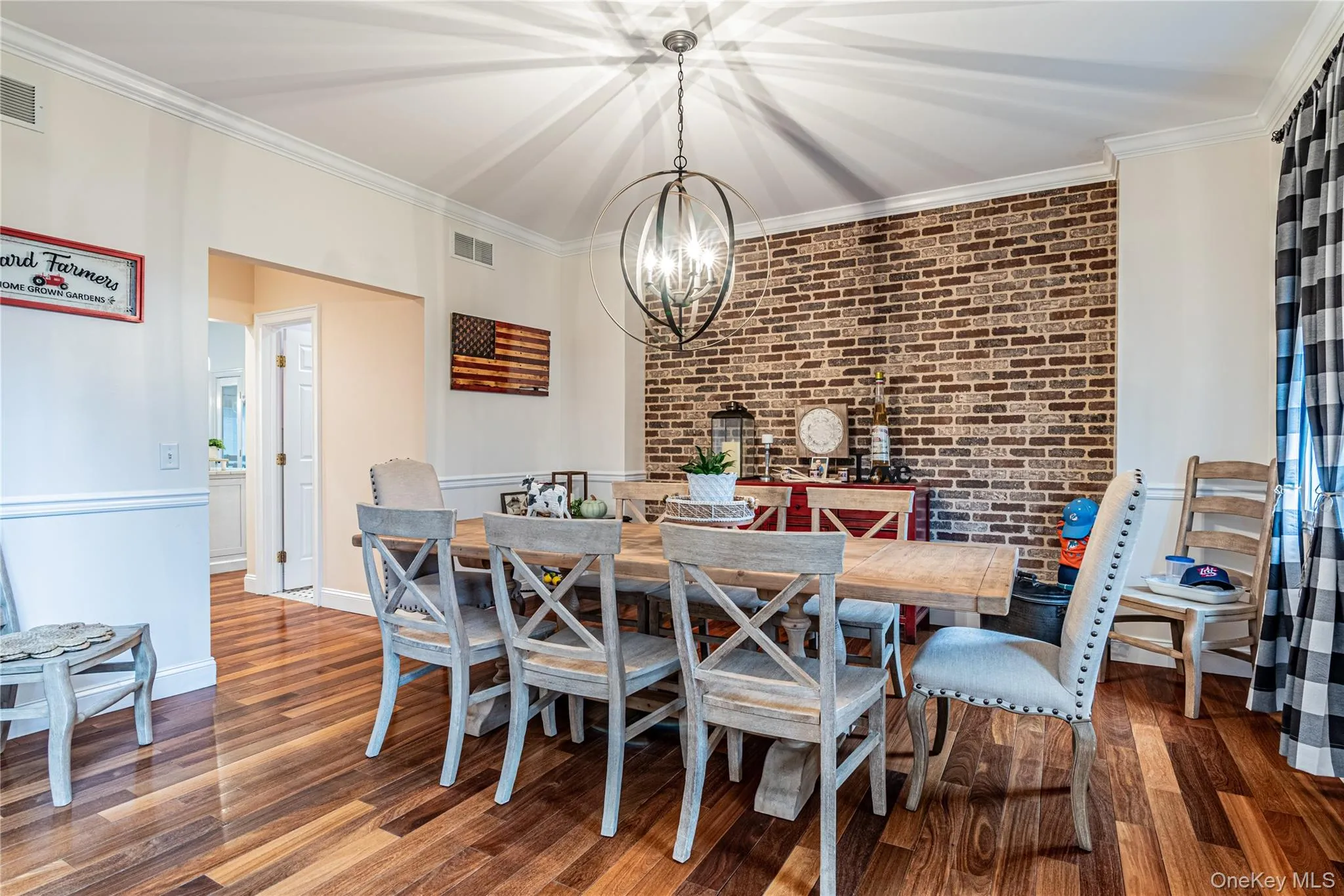 Dining room with crown molding, dark wood finished floors, suspended lighting, and brick wall Dining room with crown molding, dark wood finished floors, suspended lighting, and brick wall