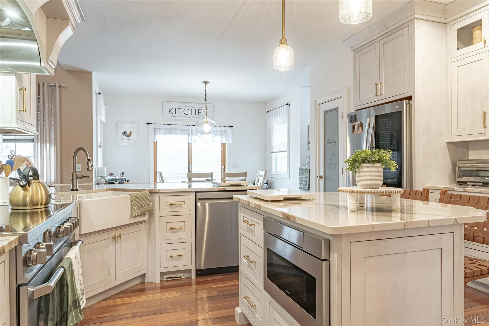 Kitchen with light stone countertops, stainless steel appliances, and decorative light fixtures Kitchen with light stone countertops, stainless steel appliances, and decorative light fixtures
