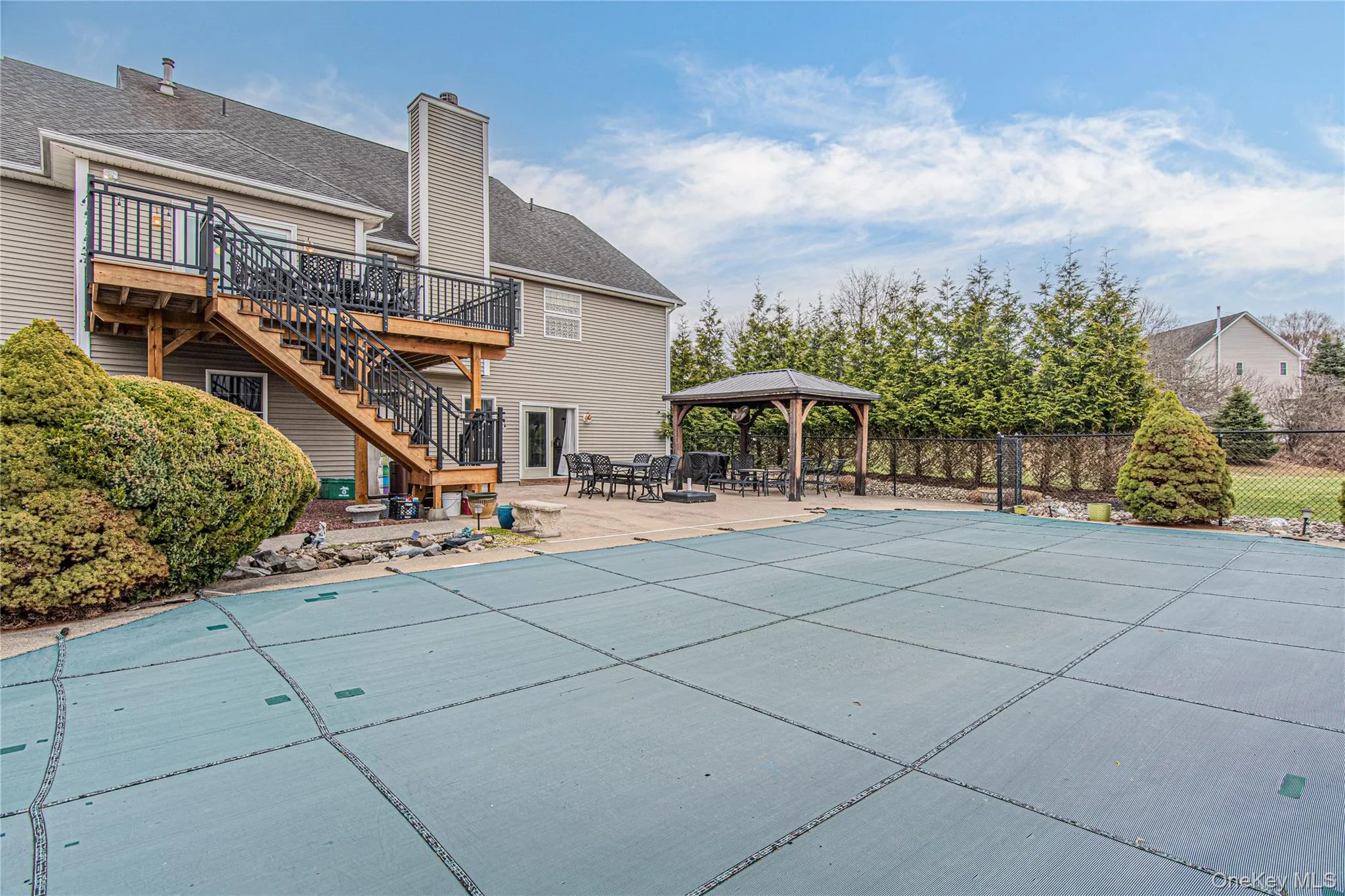 Rear view of property featuring a patio, pool, a gazebo, a chimney, and a deck Rear view of property featuring a patio, pool, a gazebo, a chimney, and a deck