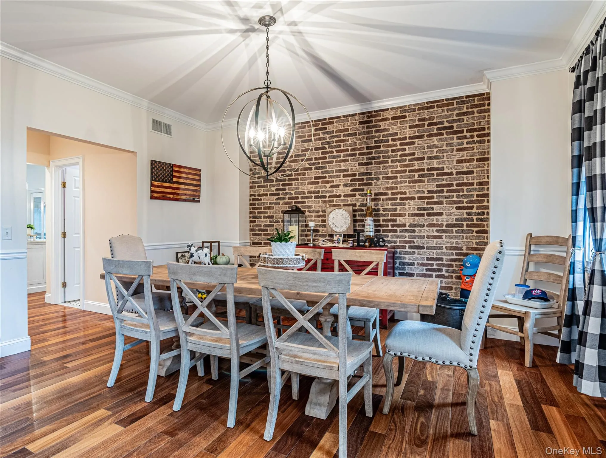 Dining space with crown molding, beautiful wood-style floors, brick wall, and suspended lighting Dining space with crown molding, beautiful wood-style floors, brick wall, and suspended lighting