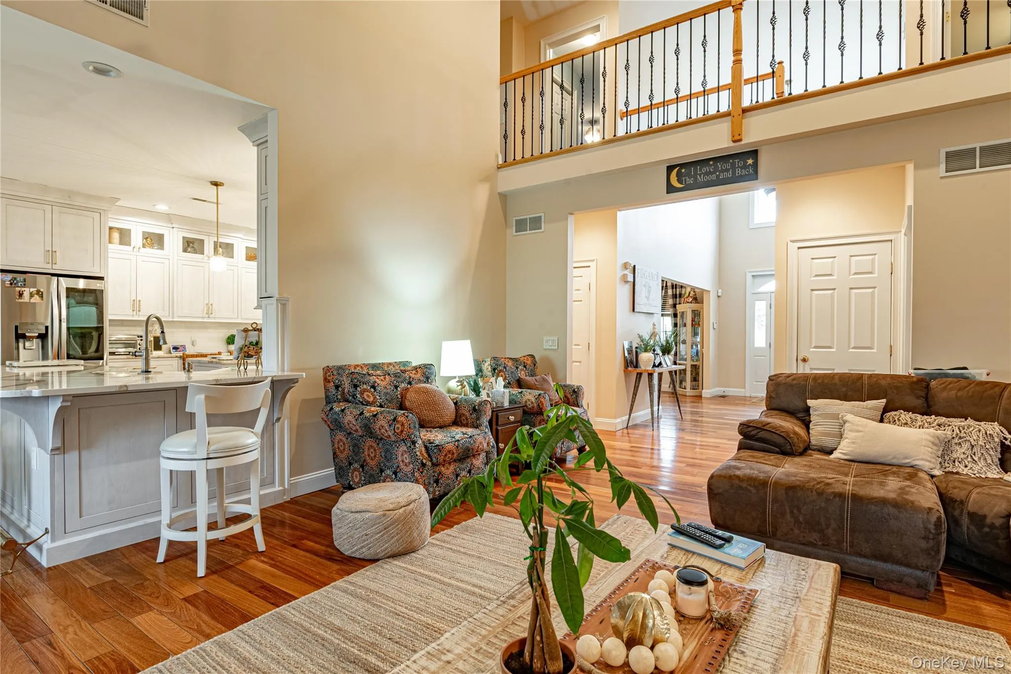 Living area featuring light wood floors and a high ceiling Living area featuring light wood floors and a high ceiling