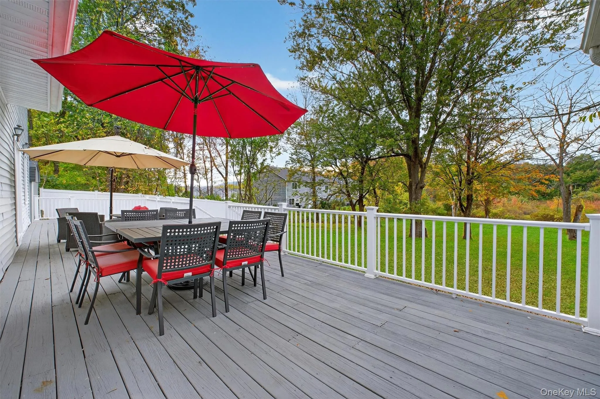 Wooden terrace featuring a lawn and outdoor dining space Wooden terrace featuring a lawn and outdoor dining space