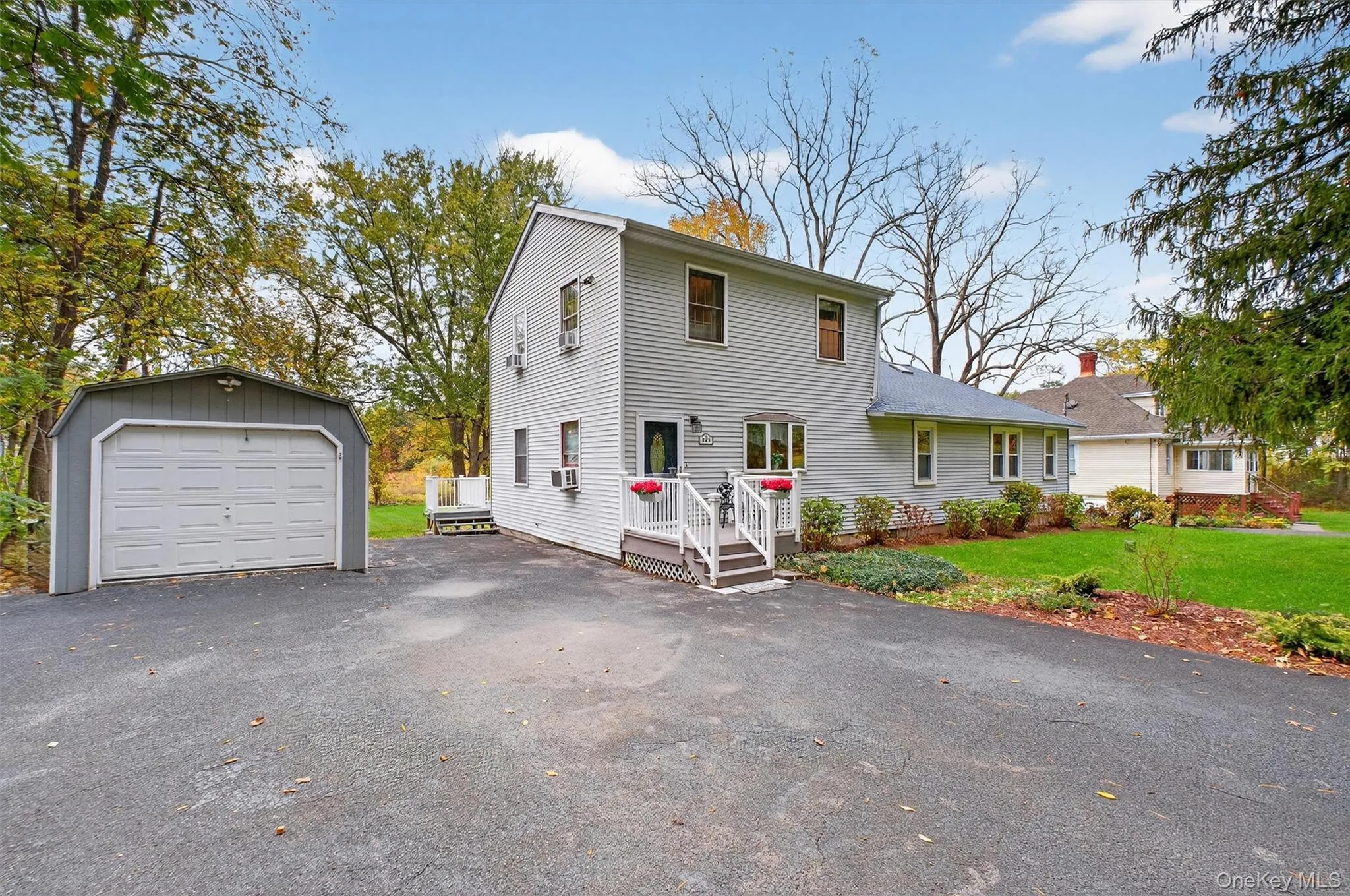 View of front of property featuring an outbuilding, asphalt driveway, a front yard, and a detached garage View of front of property featuring an outbuilding, asphalt driveway, a front yard, and a detached garage